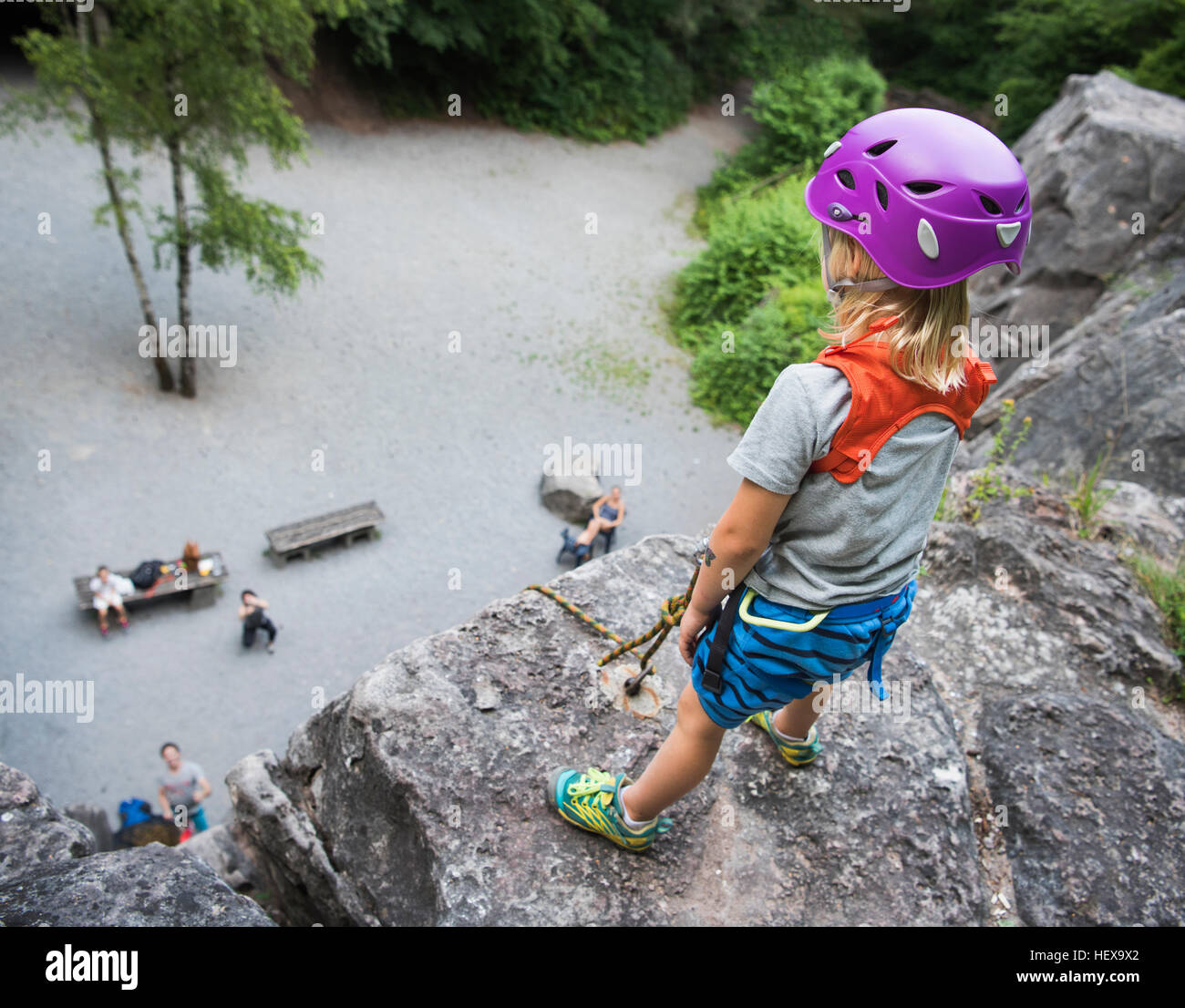 Casque d'escalade boy standing on top of rock à la bas Banque D'Images