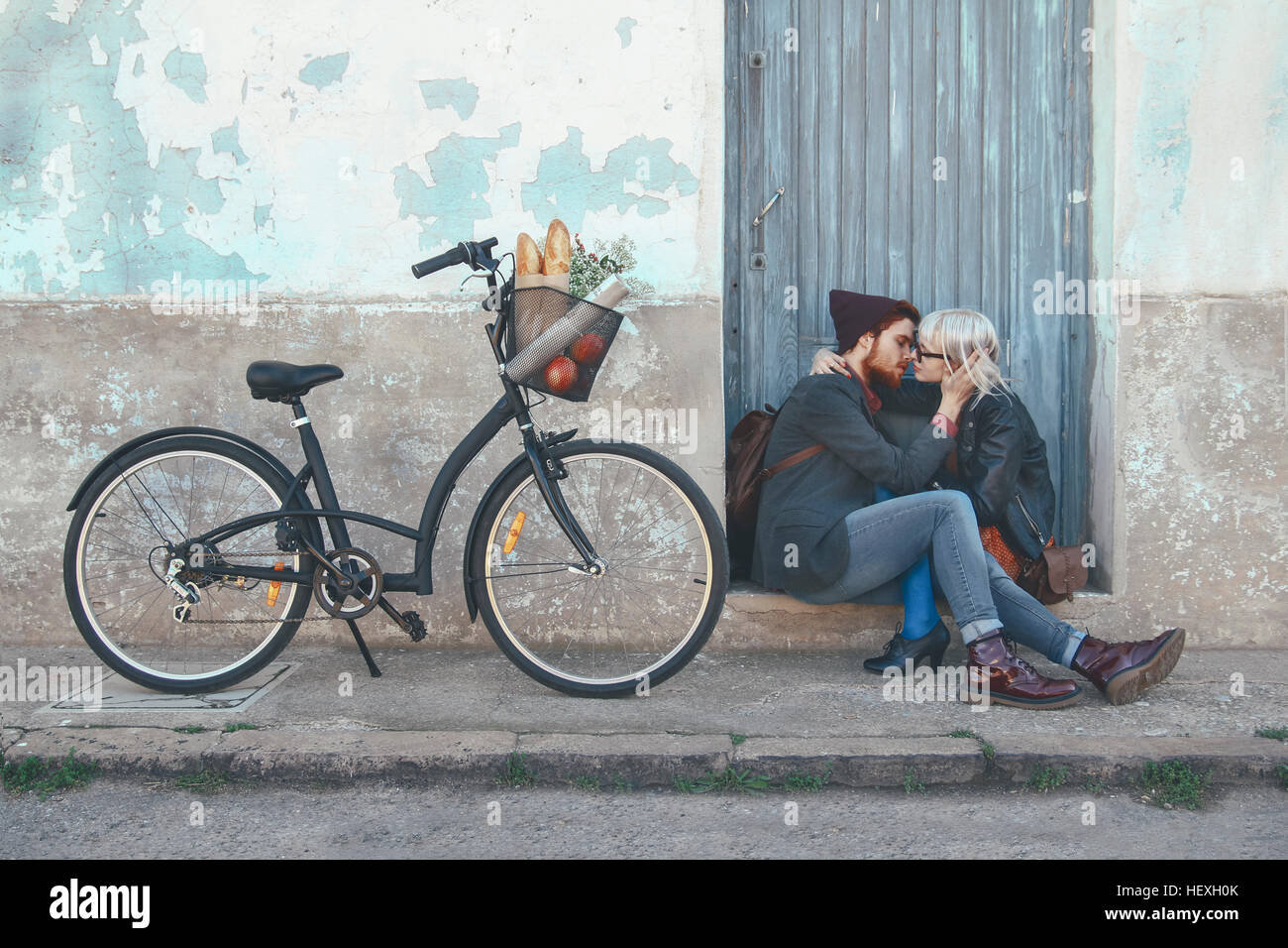 Jeune couple dans l'amour, baiser sur l'étape de porte à côté d'un vélo Banque D'Images