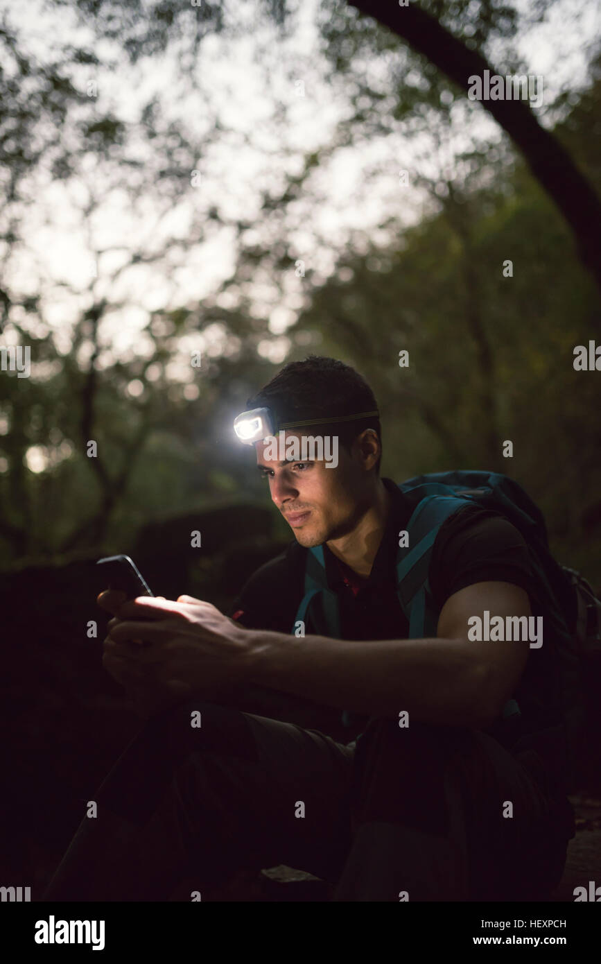 Randonneur avec un projecteur dans la forêt à la recherche sur smartphone Banque D'Images