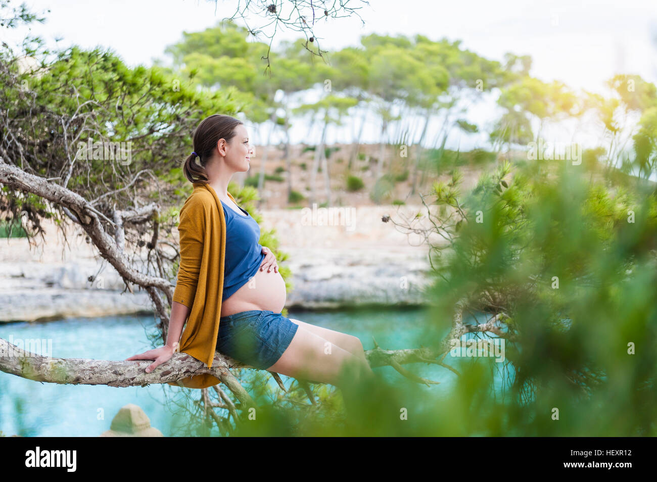 Pregnant woman sitting on branche à la mer Banque D'Images
