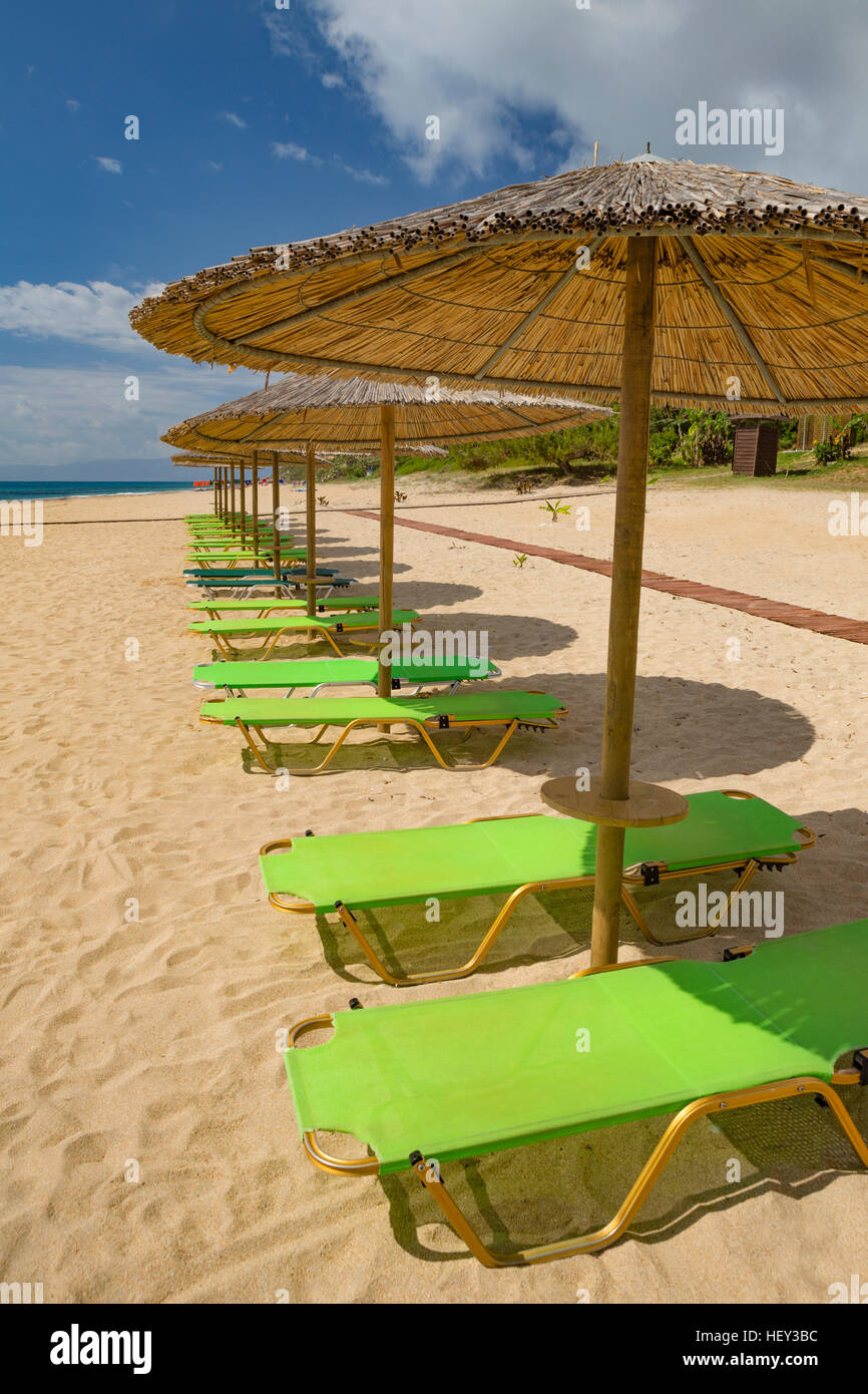 Chaises longues et parasols dans une rangée sur la plage de sable de Skala, Kefalonia, Grèce Banque D'Images