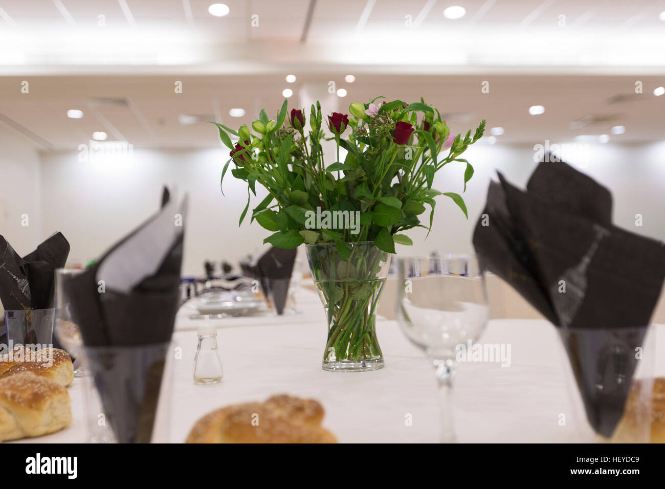 Thème noir et blanc table célébration simcha challah avec petits pains et vase de fleurs rose rouge Banque D'Images