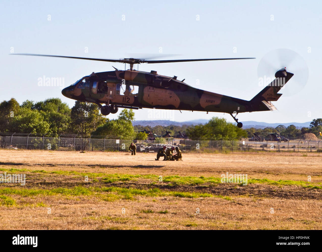 Les équipes médicales de la Royal Australian Air Force Air Medical Team, 3e soutien santé Battlion, AQ, la Force des États-Unis et de marins de la 3e Bataillon Médical, partie de III Marine Expeditionary Force, basée à Okinawa, Japon, effectuer le "deux-man' de treuil de sauvetage un UH-60 Blackhawk 5e Régiment d'avaition de Townsville, Queensland, planant au-dessus d'un champ d'herbe au Camp Rocky à Rockhampton. Les titres de formation de sauvetage sont une partie de la société Talisman Saber 2011. TS11 est un combiné biennale de l'activité de formation visant à former les forces australiennes et américaines combinées à la planification et à la conduite Banque D'Images
