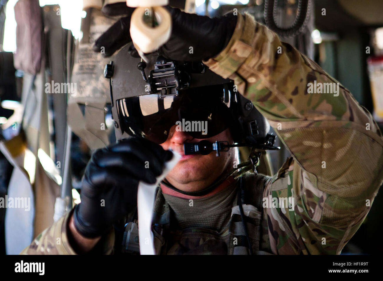 La CPS. Ryan Waller, arômes, en Californie, des autochtones et de vol infirmier de la Compagnie Charlie, 1-168e soutien général Aviation Battalion, arrache une bande de sparadrap à l'intérieur d'un UH-60 Black Hawk en volant un soldat afghan blessé au Camp Bastion, dans la province d'Helmand, en Afghanistan, le 14 novembre 2013. Le soldat a subi une blessure abdominale durant un échange de tirs et a reçu des soins d'urgence de médecins de l'Armée nationale afghane et de la Marine avant d'être Corpsmen en avion au Camp Bastion. E28098Golden HourE28099 Vol, vitesse infirmiers patients traumatisés off battlefield 131114-M-ZB219-051 Banque D'Images
