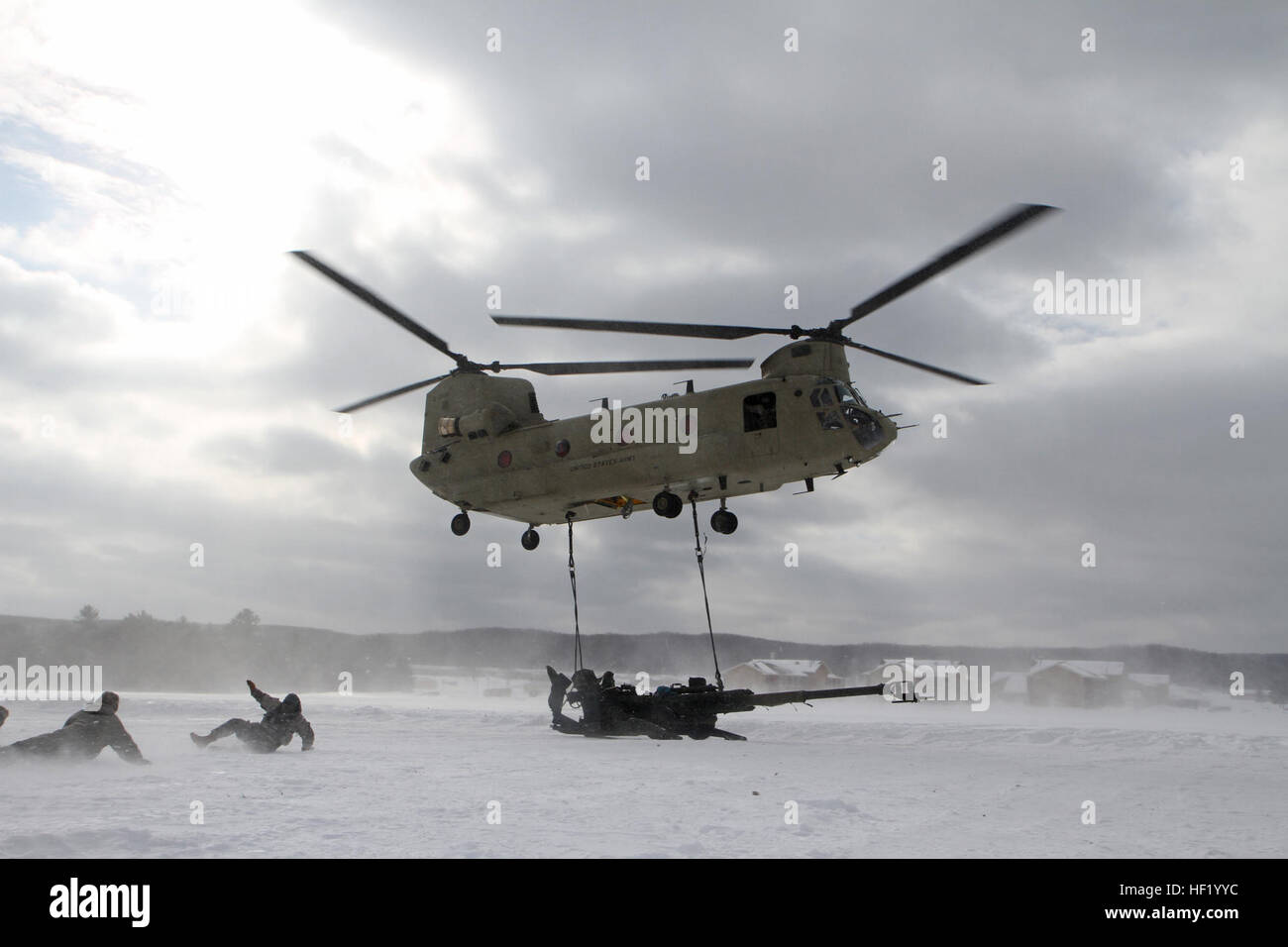 Les soldats du 1er bataillon du 119e Régiment d'artillerie, de retraite, de dessous un CH-47 Chinook après une slingloading howtizer M-777 155mm pendant le fonctionnement par temps froid à l'ombre du Camp d'entraînement aux Manœuvres conjointes Centre, Mich., Mar.1, 2014. La température de l'air était de 30 degrés Celsius en dessous de zéro, les vents sous les pales étaient de 140 miles par heure, et le refroidissement éolien sous l'hélicoptère atteint quatre-vingt-dix degrés négatifs. Michigan (photo de la Garde nationale par le sergent. Kimberly Bratic/libérés) Michigan Garde nationale mène la charge sous élingue par temps froid et l'exercice de tir réel d'obusiers 140301-LE-Z308-029 Banque D'Images