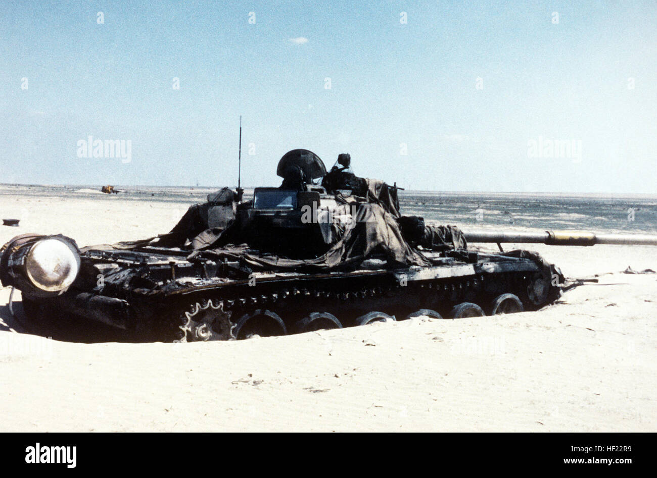 Un Irakien endommagé le char de combat principal T-72 drapé avec des morceaux de filet de camouflage se trouve dans le désert après avoir été abandonné pendant l'opération Tempête du désert. Endommagé UN T-72 irakien revêtu de morceaux de filet de camouflage Banque D'Images