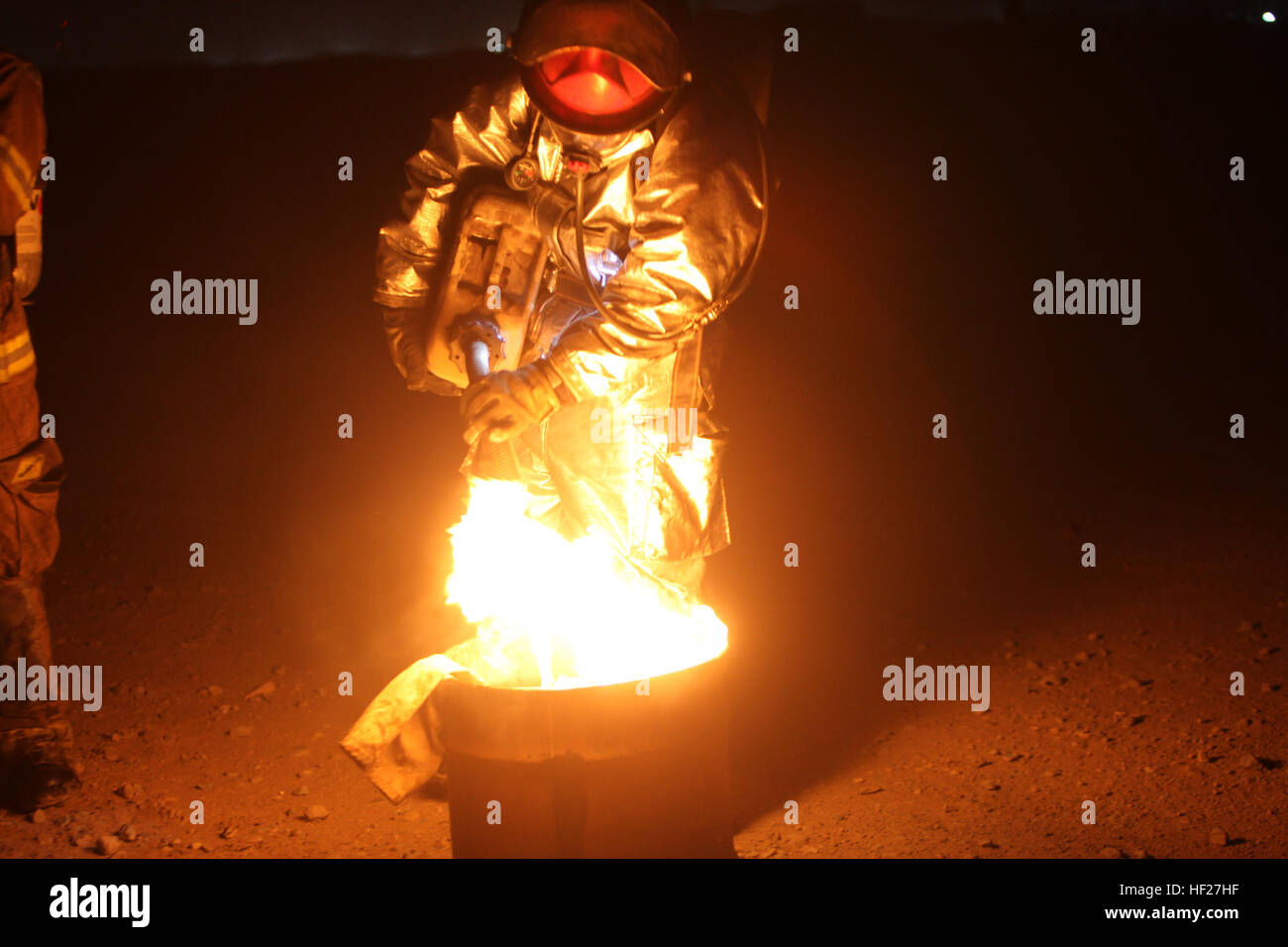 Une armée de l'air le feu et d'intervention d'urgence avec le conseiller conseiller 738e Escadron expéditionnaire de la jette de l'huile sur un petit seau fire simulant des débris de l'avion au cours d'un exercice de tir réel de nuit à bord, l'Afghanistan, le Camp de Shorabak 7 Juin, 2014. Les soldats de l'Armée nationale afghane font partie du Camp Shorabak Service d'incendie. L'exercice d'un écrasement d'aéronef simulés avec de multiples petites forêt entourant l'incendie d'aéronefs pour les soldats à supprimer. (U.S. Marine Corps Photo : Sgt. Frances Johnson/libéré) les pompiers de l'Armée nationale afghane blaze grâce à l'entraînement au tir réel 140607-M-JD595-0 Banque D'Images