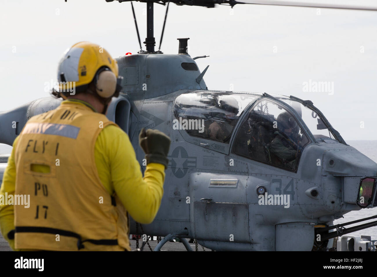 Un manœuvrier aviation signaux manuels pour le Capitaine de vaisseau Jim E. McGovern, commandant de l'USS Iwo Jima, avant, et Marine Corps Le Capitaine Brian Fredo, un pilote, AH-1 qualifié, avec l'escadron 365 à rotors basculants moyen maritime (renforcée), 24e Marine Expeditionary Unit, à bord du USS Iwo Jima le 9 octobre 2014. Le vol, réalisés à l'AH-1W Super Cobra, a été réalisée en collaboration avec l'unité de formation combinées de l'exercice dans le cadre des préparatifs de la 24e MEU's prochain déploiement à la fin de l'année. (U.S. Marine Corps photo par le Cpl. Todd F. Michalek) 24e MEU mène des opérations de vol 141009-M-YH418-048 Banque D'Images