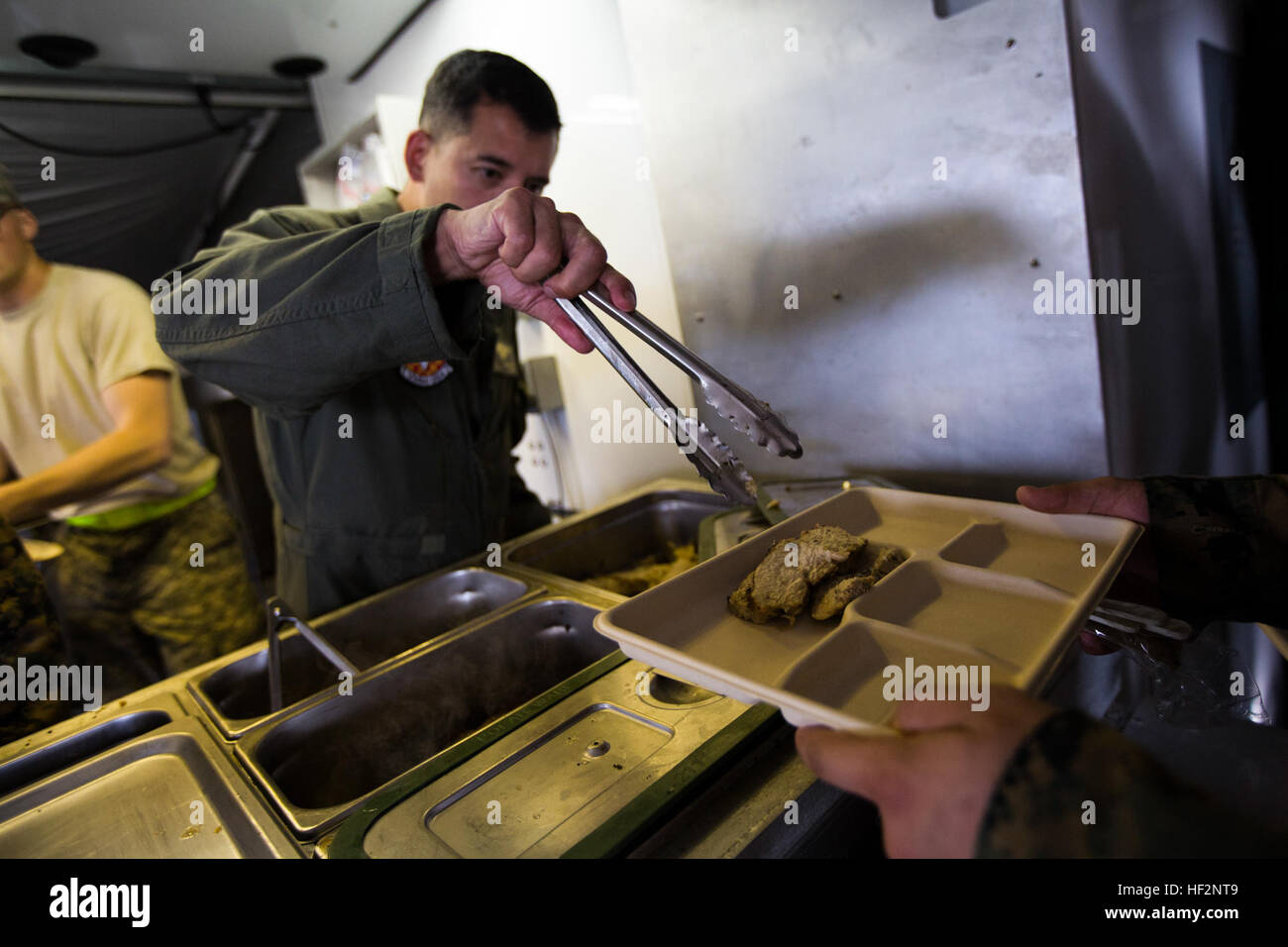 Le Lieutenant-colonel du Corps des Marines américain Colin Brainard, SPMAGTF - Réponse aux crises de l'aviation de l'Afrique de l'élément de combat, commandant de marine et sert un repas de Thanksgiving de marins pour célébrer les fêtes de alors que dans le cadre de l'opération United Assistance à Monrovia, au Libéria, le 27 novembre 2014. United Assistance est une opération du Ministère de la Défense afin d'assurer le commandement et le contrôle, la logistique, la formation, et du soutien technique à l'Agence des États-Unis pour le développement international, a dirigé les efforts visant à contenir l'épidémie du virus Ebola en Afrique occidentale. (U.S. Marine Corps photo par Lance Cpl. Andre Dakis/SPMAGTF-CR-AF Lutter contre C Banque D'Images
