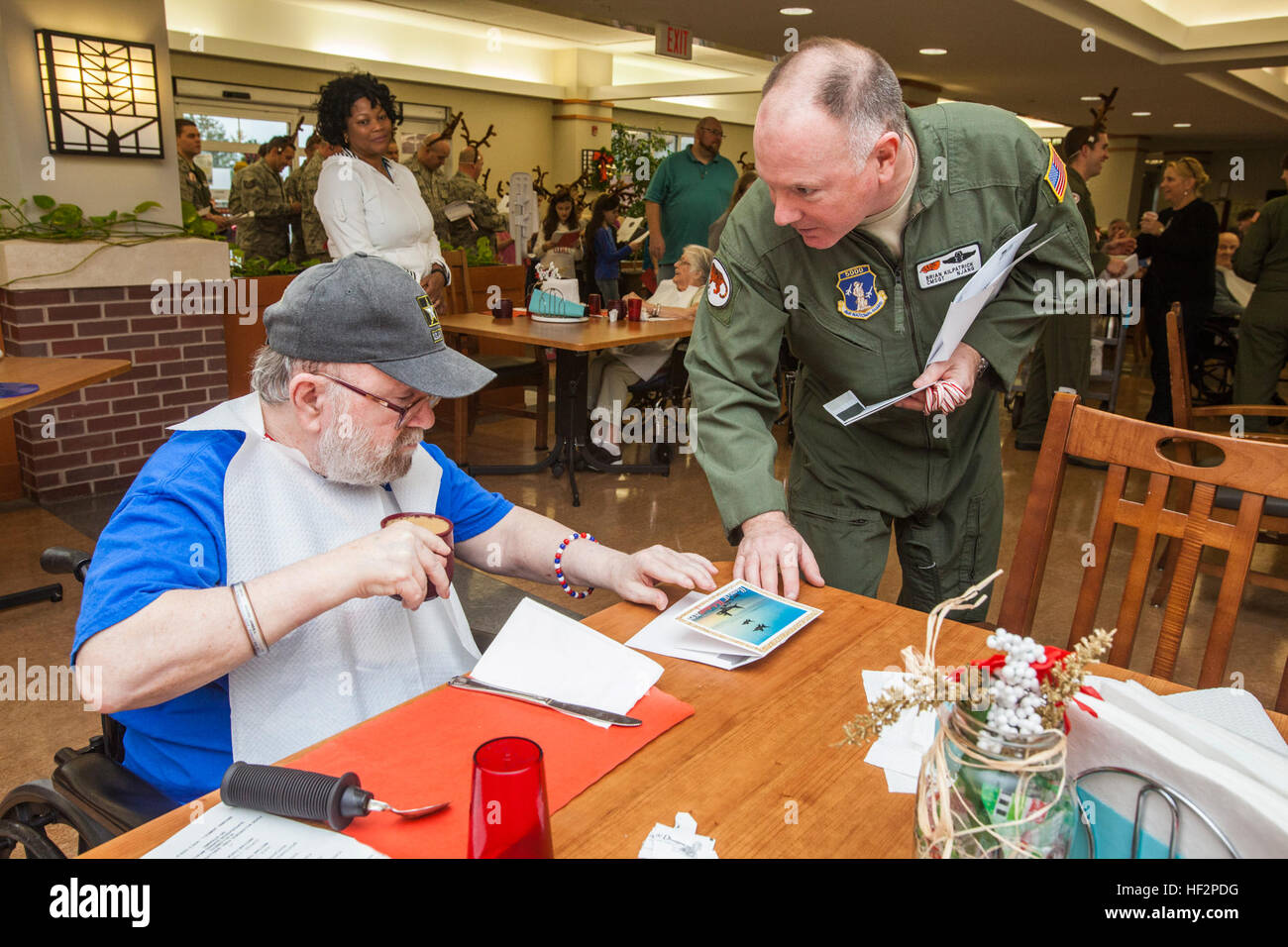 Le sergent-chef en chef. Brian Kilpatrick, 108e Escadre, donne une carte postale à un résident comme aviateurs, à partir de la 108e Escadre et de la 177e Escadre de chasse, New Jersey Air National Guard, ont été rejoints par 47 quatrième année de l'École de la mer à Linwood, N.J., pour la 14e Conférence annuelle de maison de vacances "ongfest» au Veterans Memorial Home à Vineland, N.J., le 9 décembre 2014. À l'arrivée, les 32 aviateurs et de quatrième année ont été émis des cartes de vœux et des cannes de bonbon, attribués à des groupes et envoyée pour répandre la joie parmi les résidents. (U.S. Air National Guard photo par le Sgt. Mark C. Olsen/libérés) aviateurs, de l'école ch Banque D'Images
