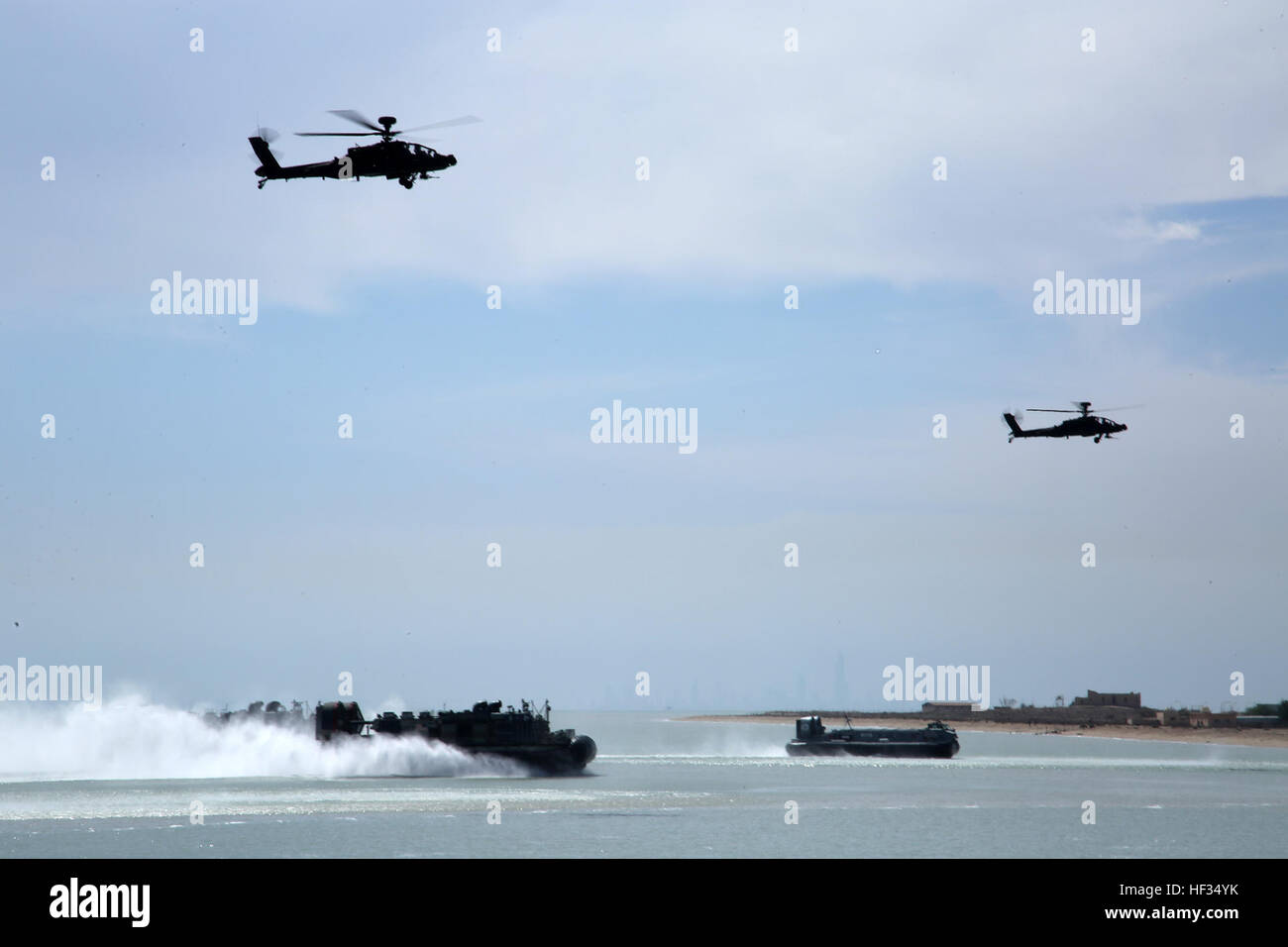 Un débarquement de la Marine américaine, aéroglisseur, gauche, fixés à l'Iwo Jima groupe amphibie, et une approche de l'aéroglisseur koweïtiens la plage tout en étant escorté par une paire d'hélicoptères Apache AH-64D au cours d'un assaut amphibie simulée dans le cadre de l'exercice 2015 Eagle résoudre à l'île de Failaka, le Koweït, le 24 mars 2015. Résoudre est la premiere Eagle Péninsule Arabe/région du golfe l'exercice entre les États-Unis, le Conseil de coopération du Golfe, l'ONU et les partenaires internationaux. Elle sert à traiter les défis associés à la guerre non/asymétrique dans une nation Banque D'Images
