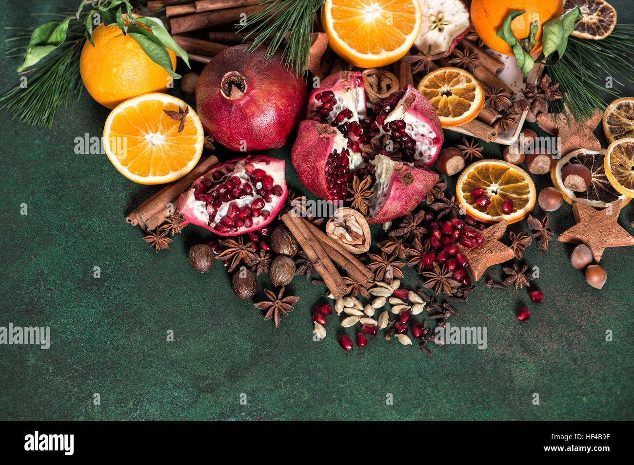 Grenade Fruits et orange avec des épices et ingrédients de la cannelle, de la badiane, cardamone, muscade sur fond rustique en pierre Banque D'Images