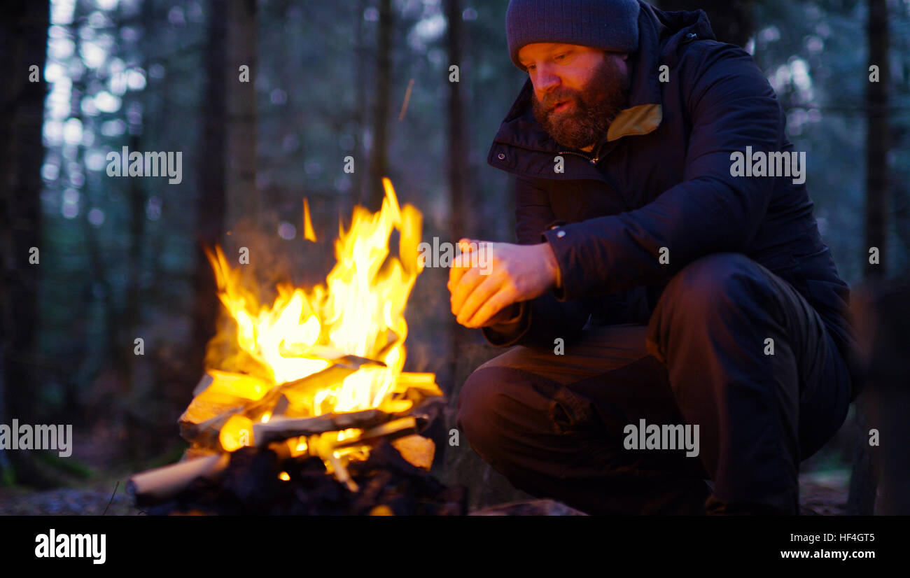 L'homme lui-même se réchauffe au feu de camp dans la forêt Banque D'Images