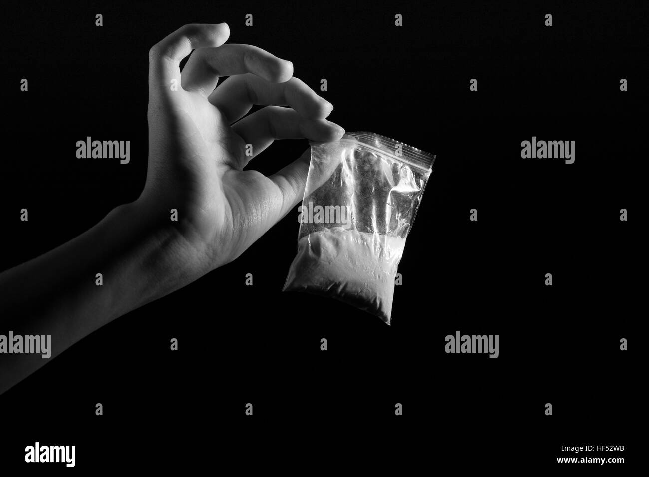 Paquet avec les stupéfiants dans la main blanche sur fond noir, l'image monochrome Banque D'Images