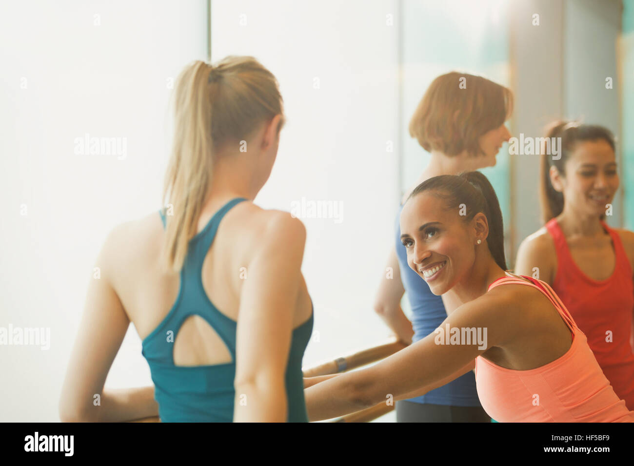 Des femmes qui parlent et qui s'étend à barre en classe d'exercice fitness studio Banque D'Images