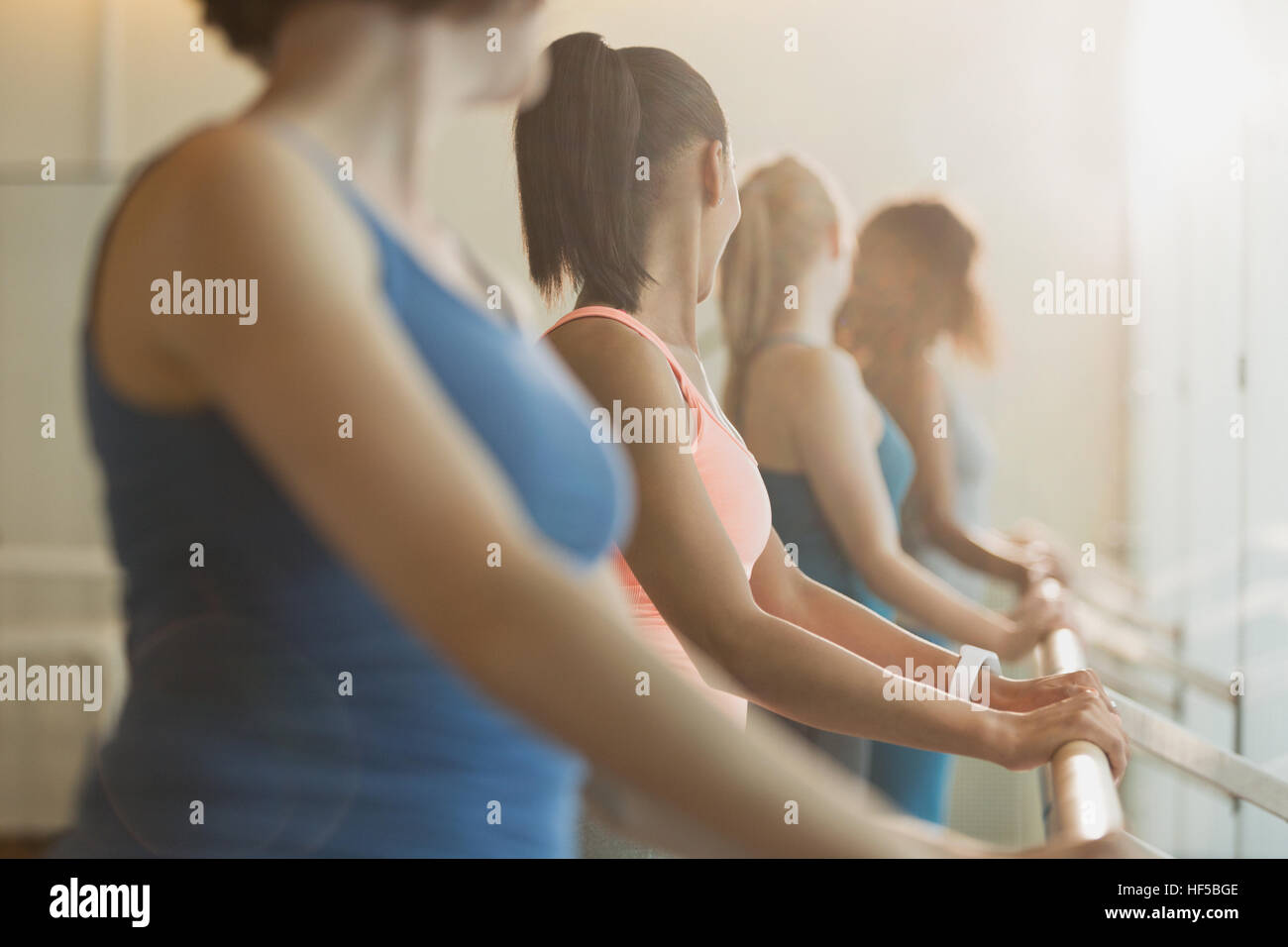 Les femmes qui s'étend au cou à barre en classe d'exercice fitness studio Banque D'Images