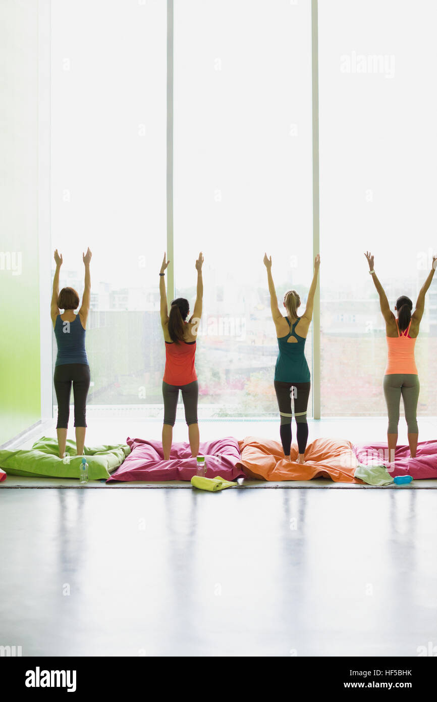 Les femmes sur des coussins qui s'étend avec bras levés dans la classe d'exercice fitness studio Banque D'Images