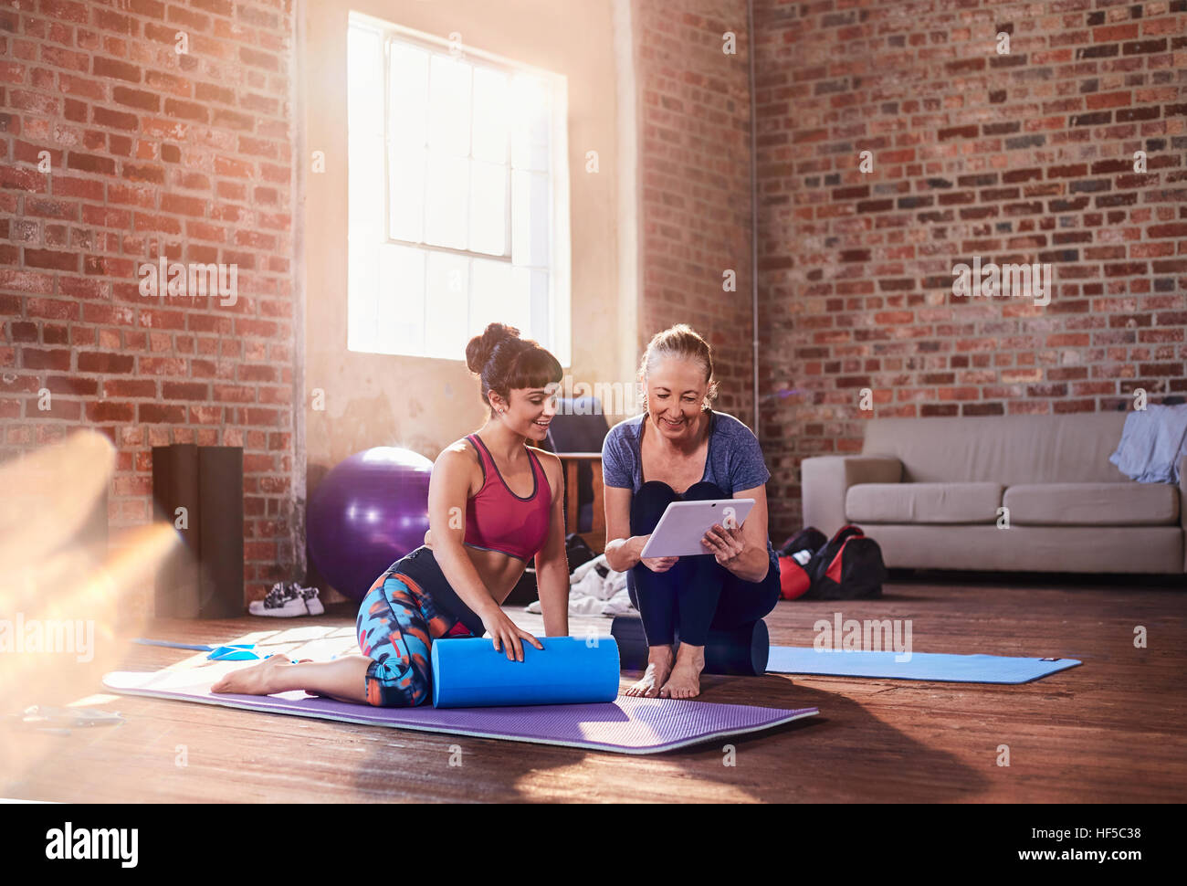 Instructeur de conditionnement physique et young woman using digital tablet in fitness studio Banque D'Images