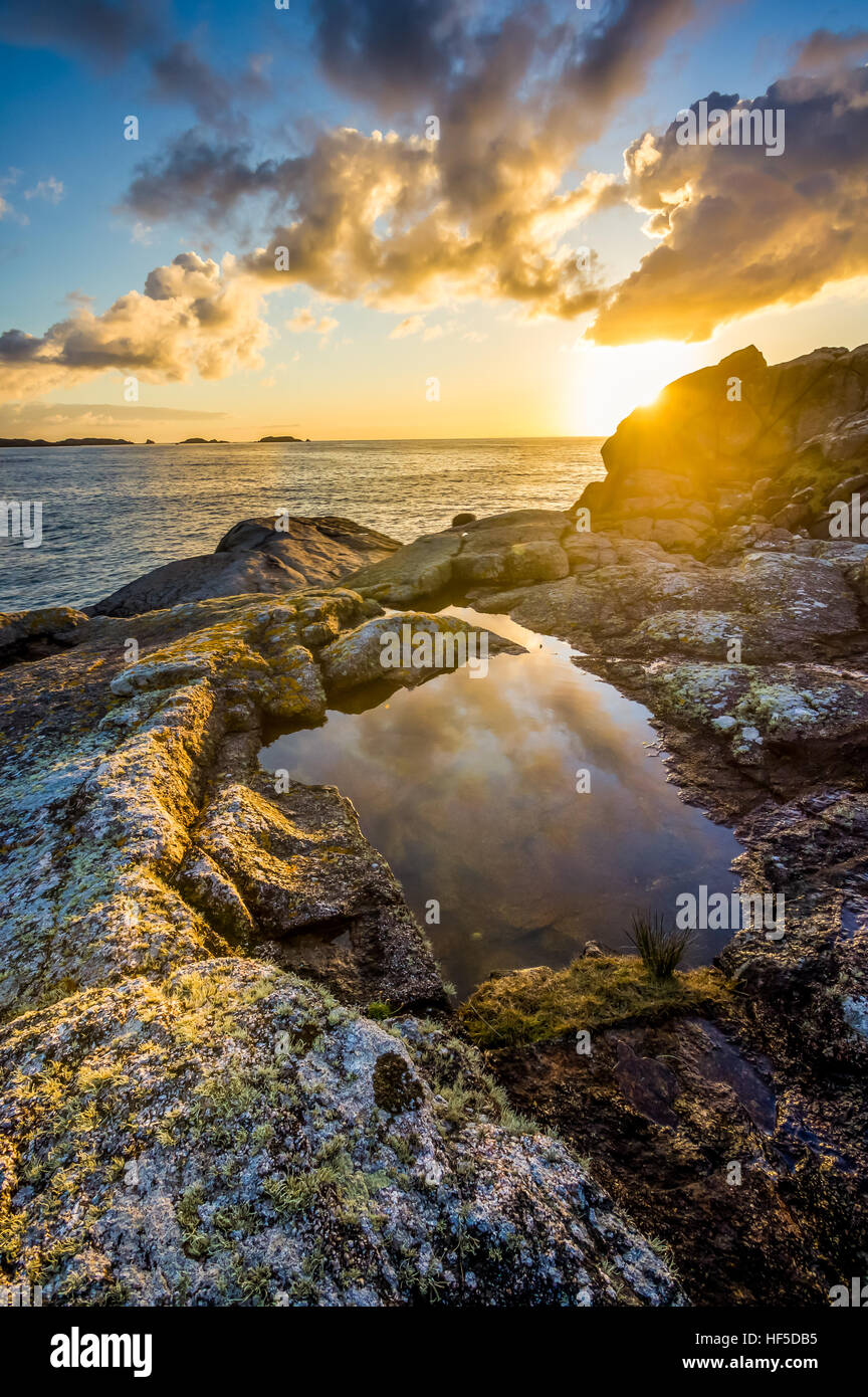 Lever du soleil reflétée dans une roche couverte d'îles dans l'arrière-plan Banque D'Images