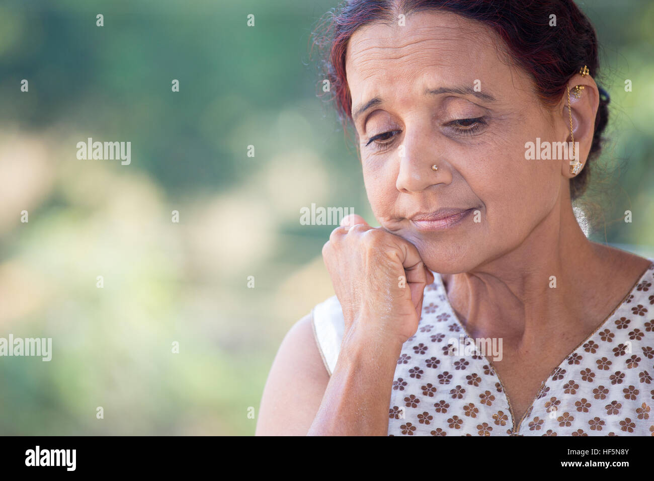 Closeup portrait dame âgée, morose, sombre, face au repos baissés sur la main, fond vert isolés à l'extérieur Banque D'Images
