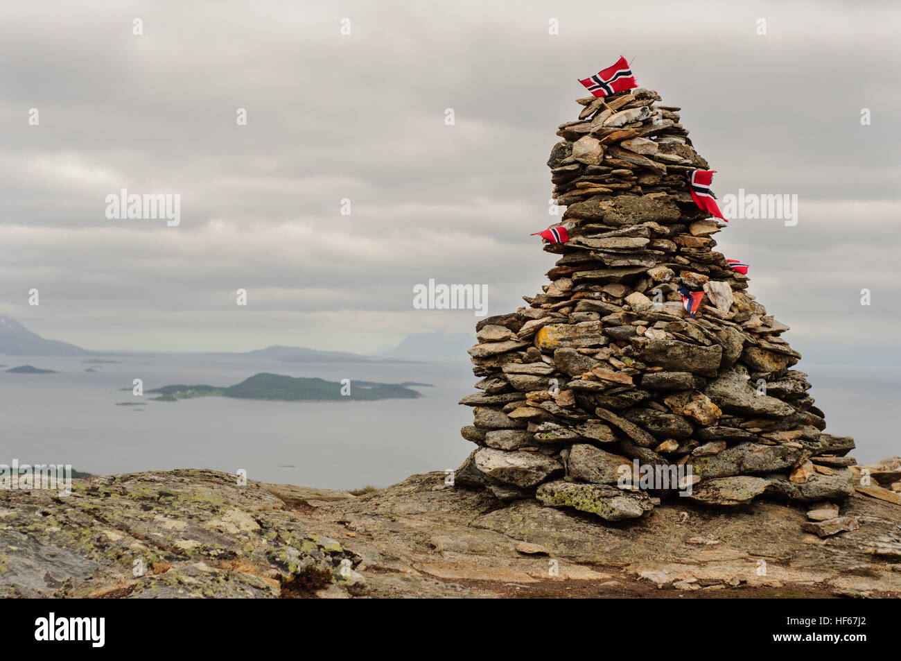 Pile de pierres avec la Norvège les drapeaux sur le sommet de la montagne dans les Lofoten, Norvège. Sur les montagnes de l'arrière-plan Banque D'Images
