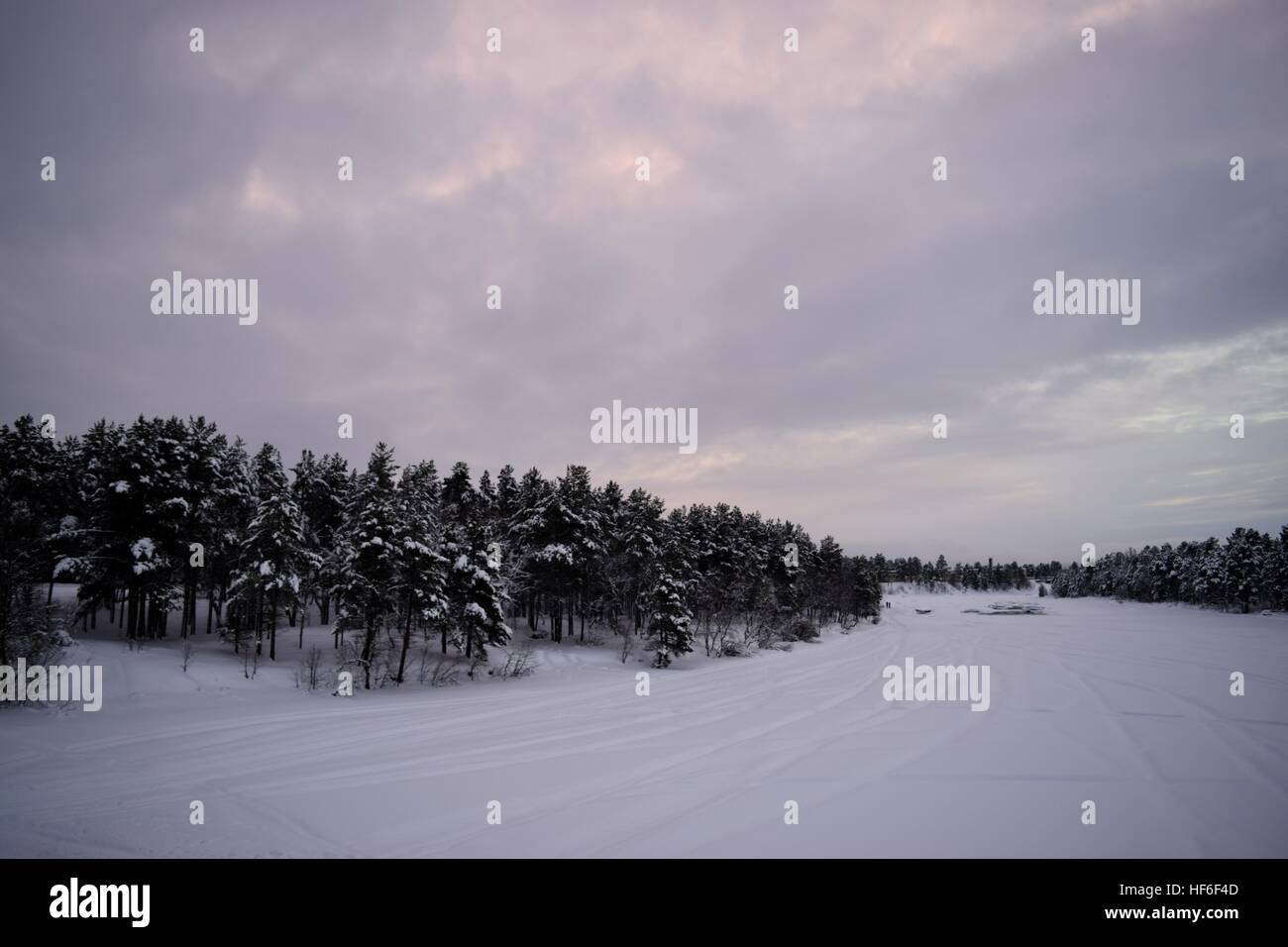 Assombri Coucher de soleil sur un lac gelé Inari, Finlande Banque D'Images