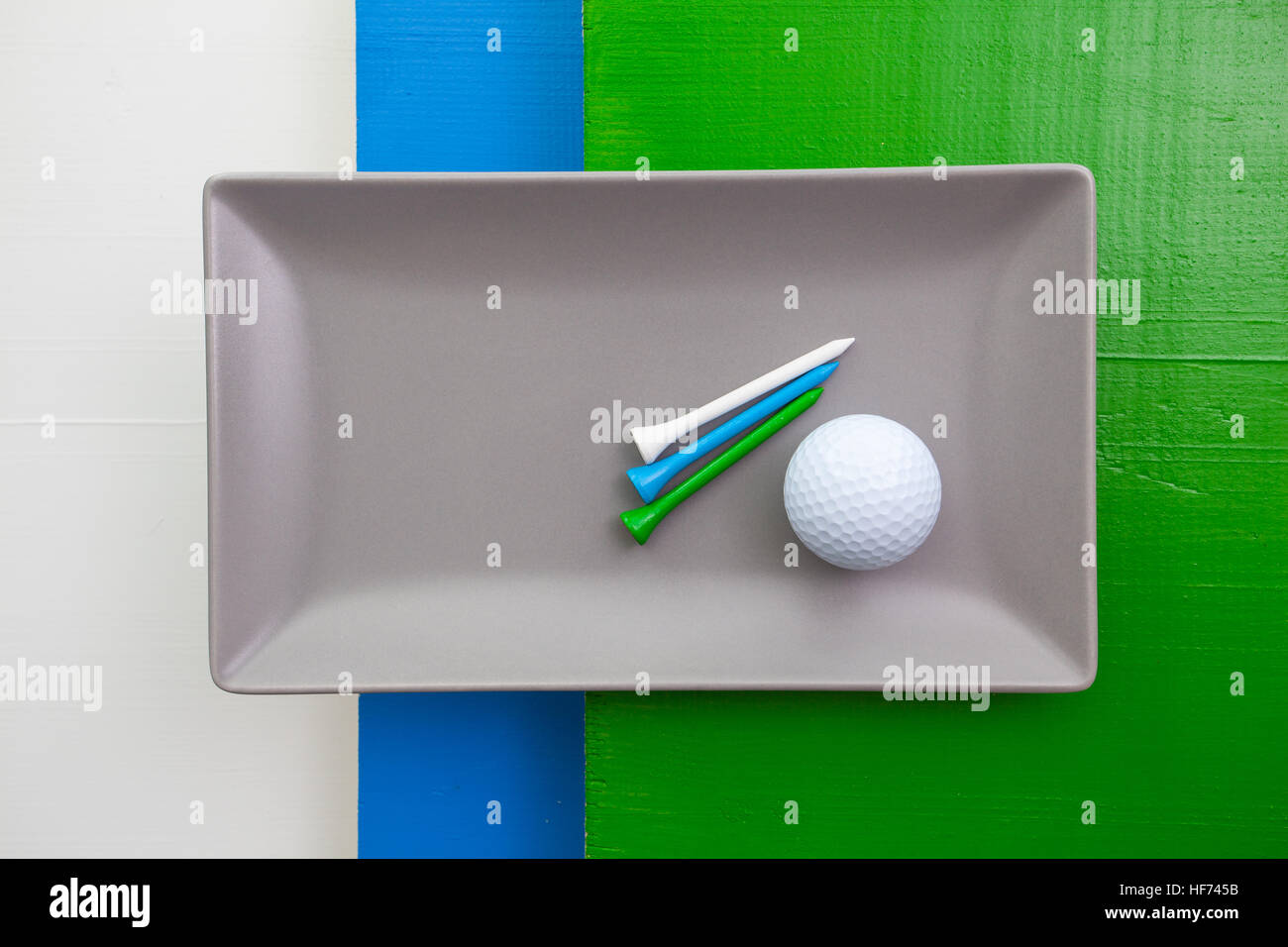 Plat de céramique gris avec des équipements de golf sur plus de blanc, bleu et vert, table en bois plat rectangle Banque D'Images