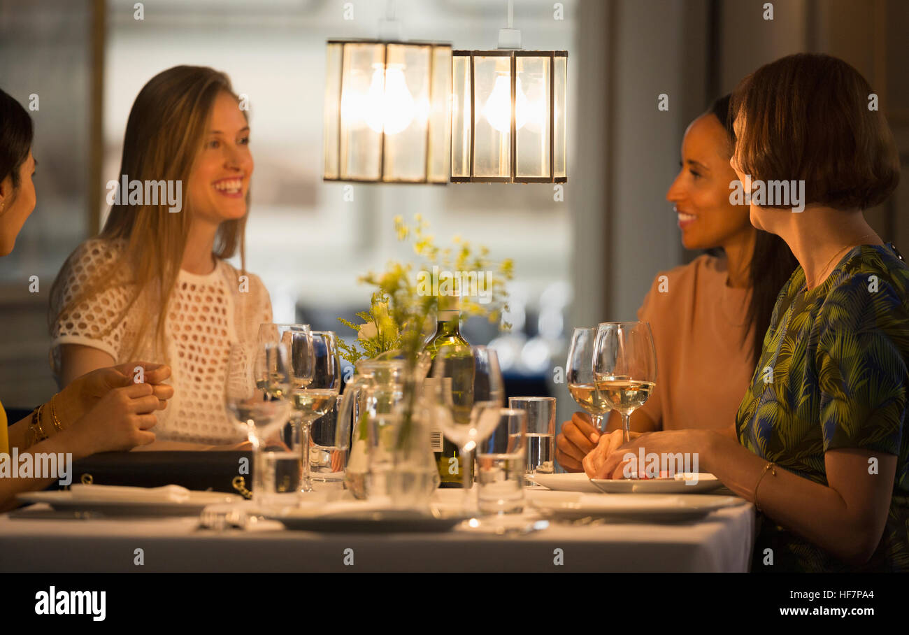 Smiling women friends coin et boire du vin au restaurant table Banque D'Images