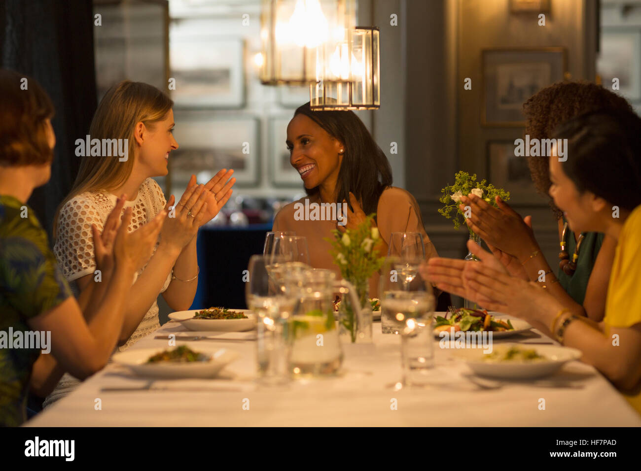 Smiling women friends coin et célébrer des mains au restaurant table Banque D'Images