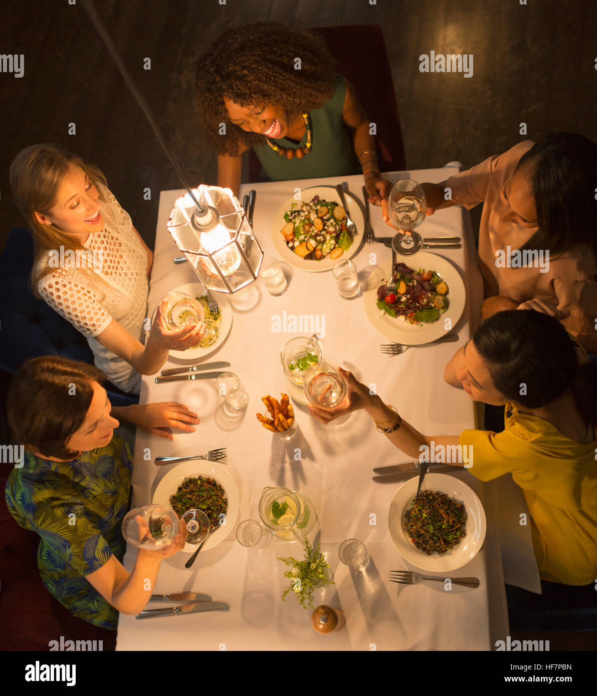 Smiling women friends toasting verres à vin de table de salle à manger au restaurant Banque D'Images