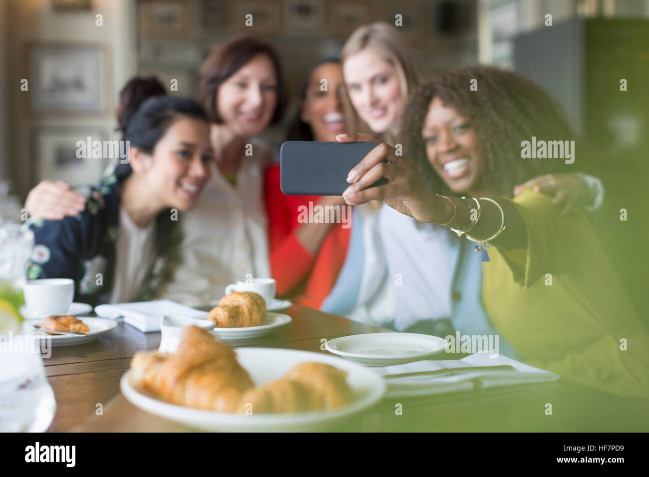 Smiling women friends avec selfies camera phone in restaurant Banque D'Images