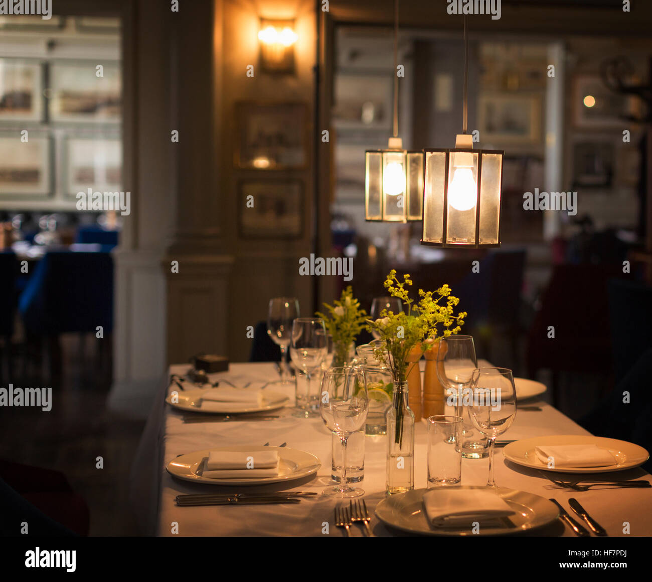 Plus placesettings lumineux suspendus sur table de restaurant Banque D'Images