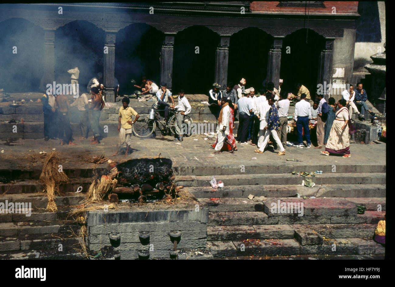 Une photographie capture le processus de crémation sur la rivière Bagmati près du temple de Pashupatinath, au Népal, avec des fleurs placées sur l'escalier comme offrandes lors d'un rituel funéraire hindou. Banque D'Images Une photographie capture le processus de crémation sur la rivière Bagmati près du temple de Pashupatinath, au Népal, avec des fleurs placées sur l'escalier comme offrandes lors d'un rituel funéraire hindou. Banque D'Images