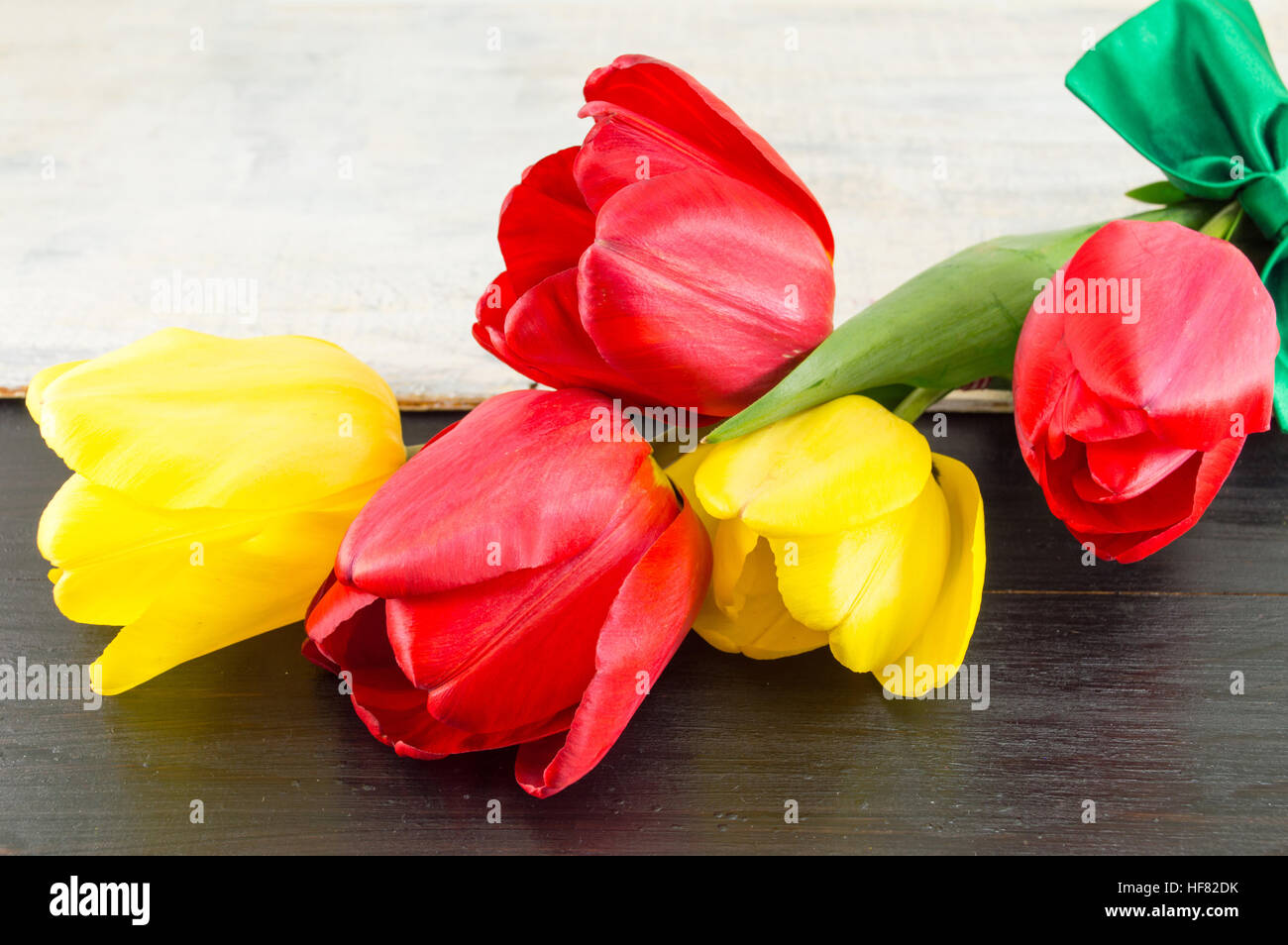 Tulipes rouges et jaunes sur une table en bois foncé Banque D'Images