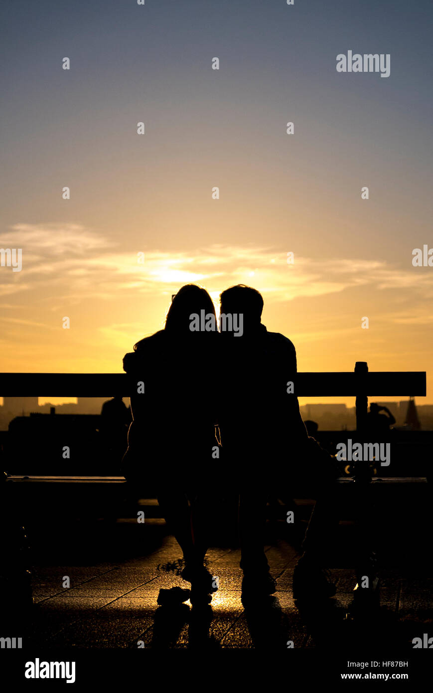Silhouette romantique de couple avec le coucher du soleil et la ville en arrière-plan Banque D'Images