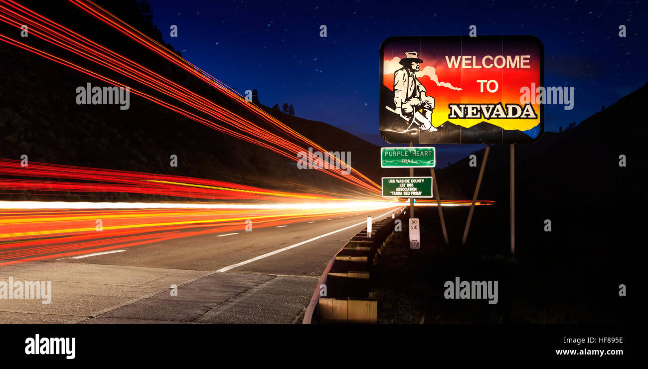 Nevada State line road sign avec une longue exposition à des sentiers de trafic la nuit. Banque D'Images