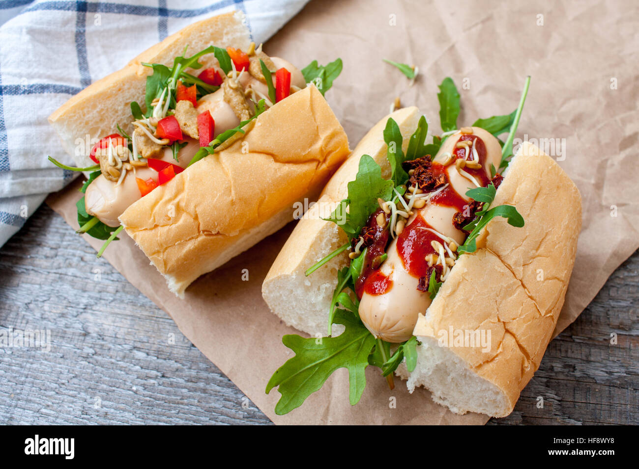 Mini hot-dogs avec des légumes sur le papier. Fond de bois, vue du dessus. Banque D'Images