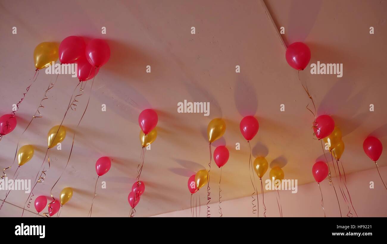 Ballons rouges suspendus au plafond jaune de vacances Banque D'Images