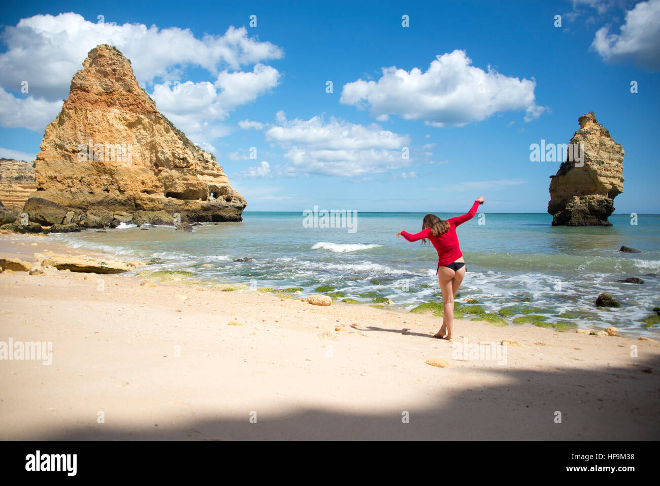 Jeune fille qui marche sur les pierres pointues sur une plage en Algarve au Portugal Banque D'Images