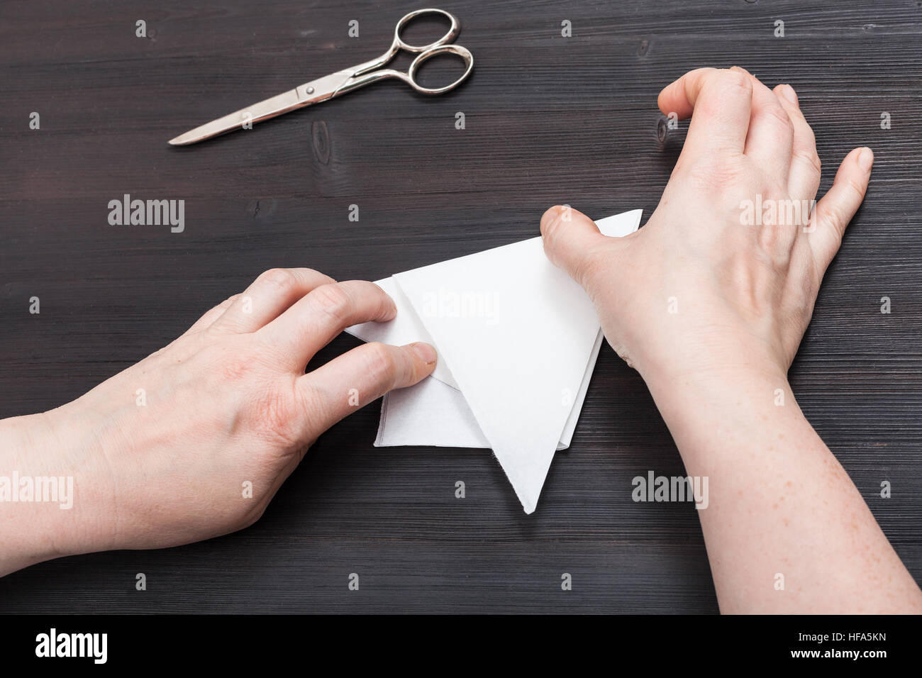 Vue de dessus de femmes double feuille de papier pour réaliser la figure sur la table en bois brun foncé Banque D'Images