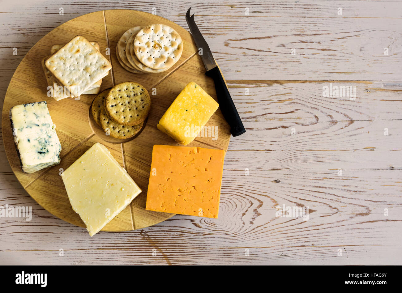 Sélection de fromages sur un plateau à fromage rond, assis sur une vieille table. Banque D'Images