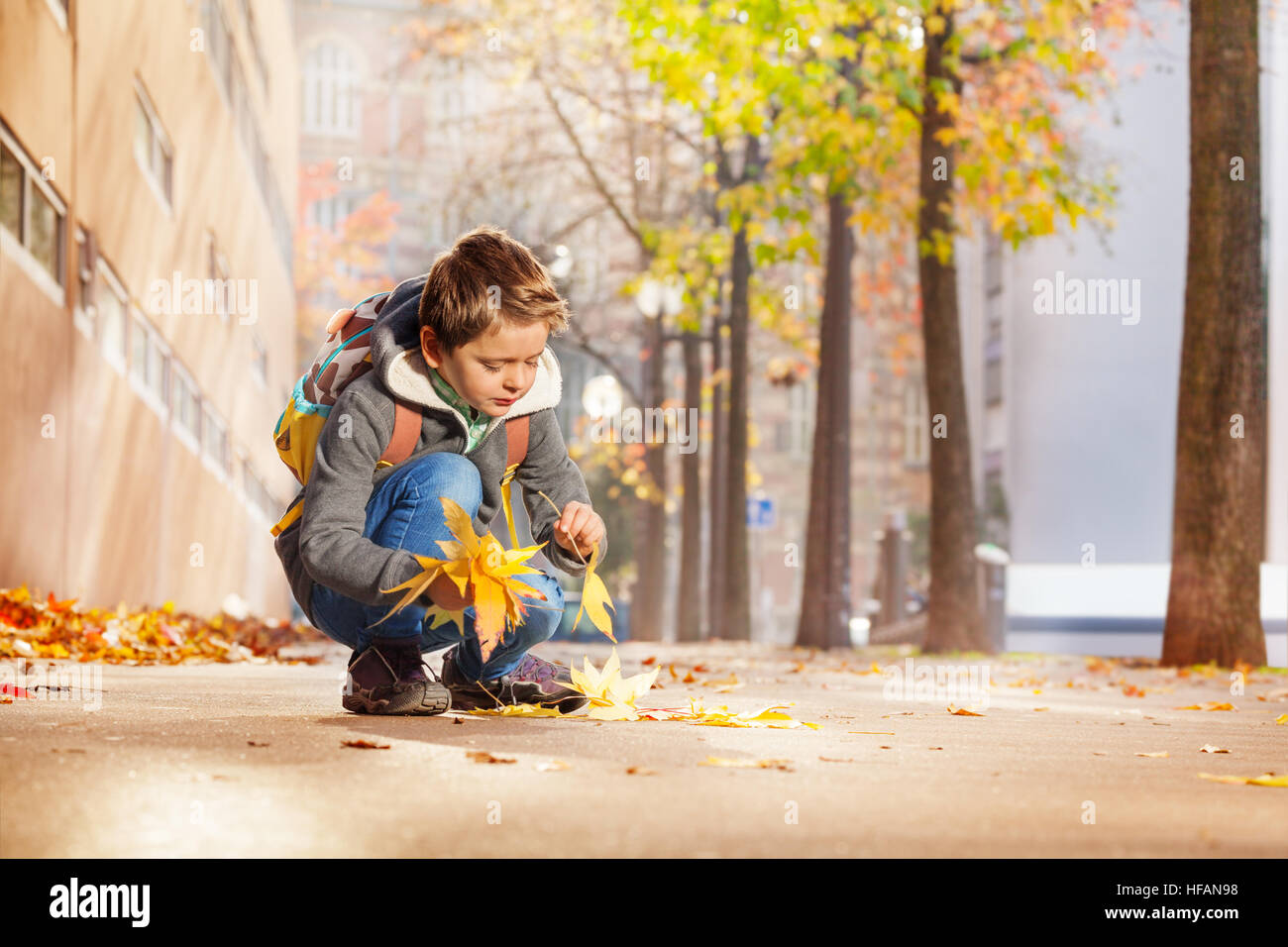 Heureux de recueillir les feuilles d'automne jaune d'écolier Banque D'Images