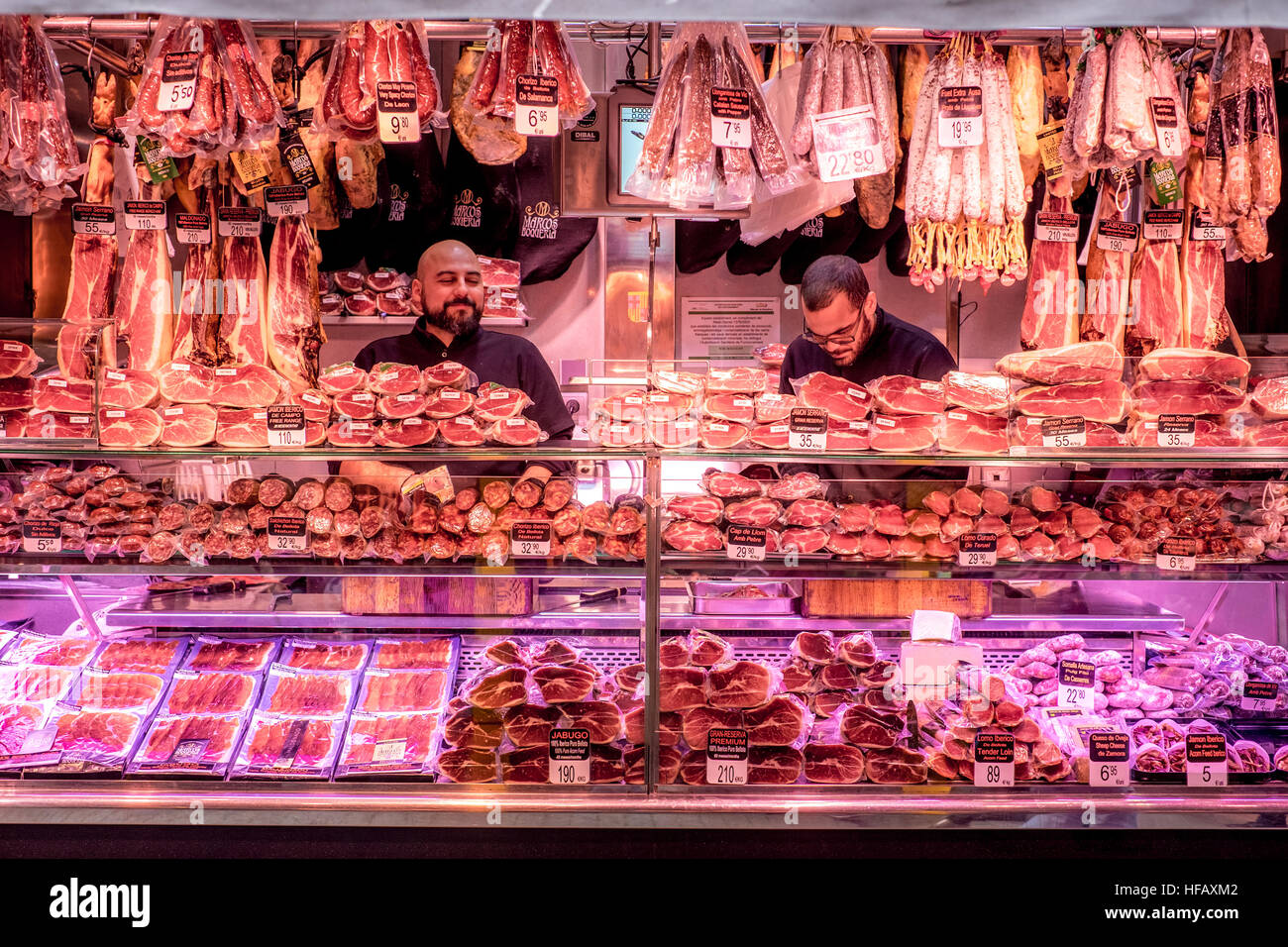 Deux bouchers fièrement leurs marchandises de jambon frais jamon au marché de la Boqueria à Barcelone, Espagne. Banque D'Images