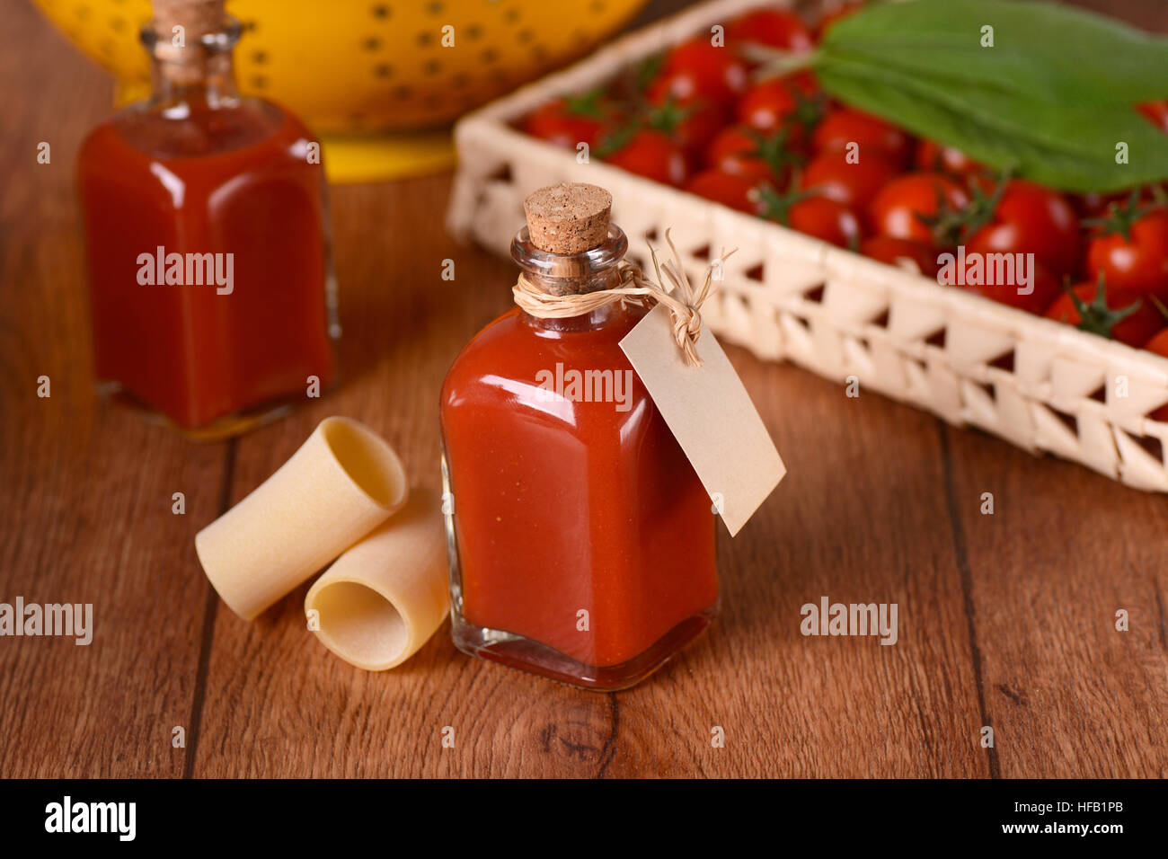 Sauce de tomates cerises dans une bouteille en verre avec des ingrédients autour de Banque D'Images