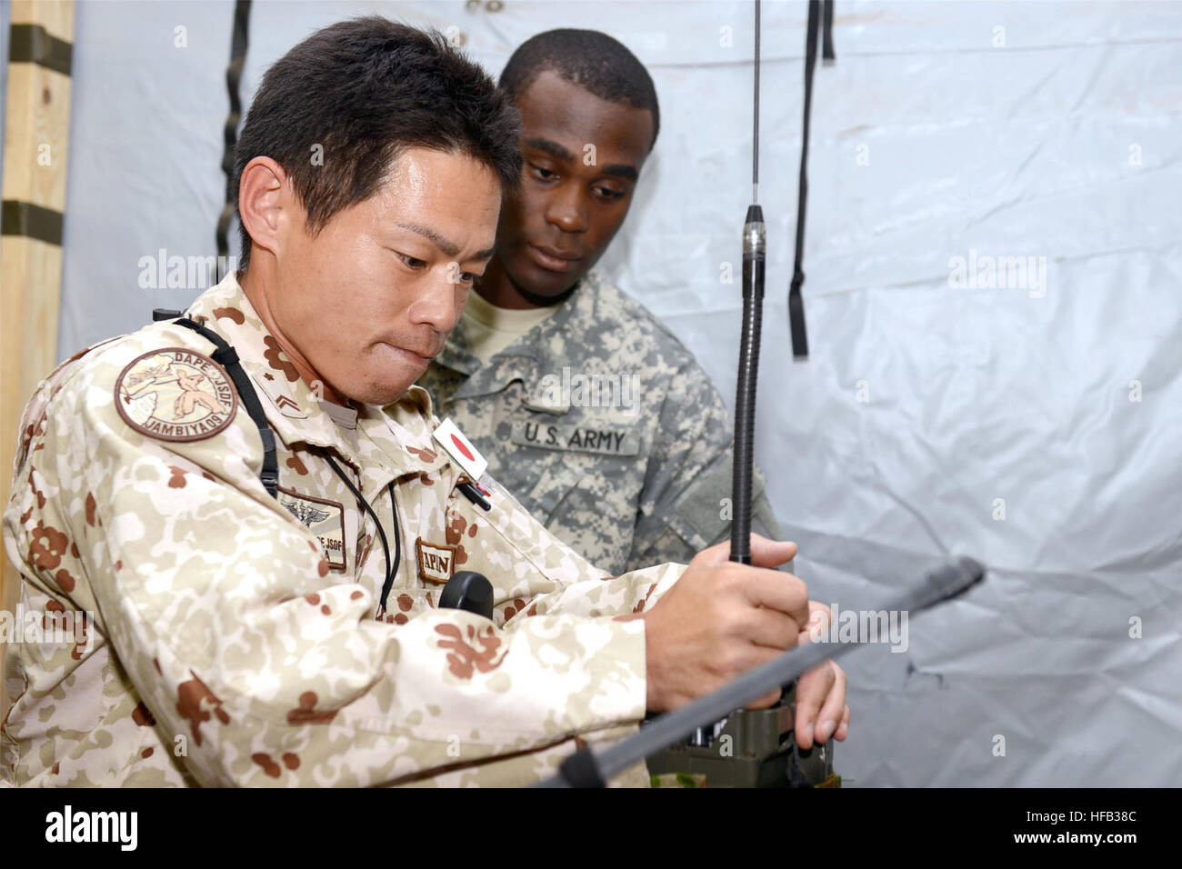 Le Japon Forces d'Autodéfense (JSDF) Le sergent de l'armée. 1re classe Yasuyuki Iwashita et le sergent de l'armée américaine. Jeffrey Smith capacité tests entre JSDF Army Field antennes radio et de champ de l'Armée américaine au Camp Lemonnier, radios Djibouti, le 5 juillet 2013. Les membres du service américain et japonais se sont réunis afin d'élaborer un système de communication d'urgence à utiliser en cas de désastres naturels ou causés par l'homme. Il assure leur service respectif's radio équipement pouvait communiquer efficacement et de manière fiable les uns avec les autres. Iwashita est un spécialiste de l'équipement de communications avec les JSDF pour Air Force de déploiement de l'ONU Application Counter-Piracy Banque D'Images