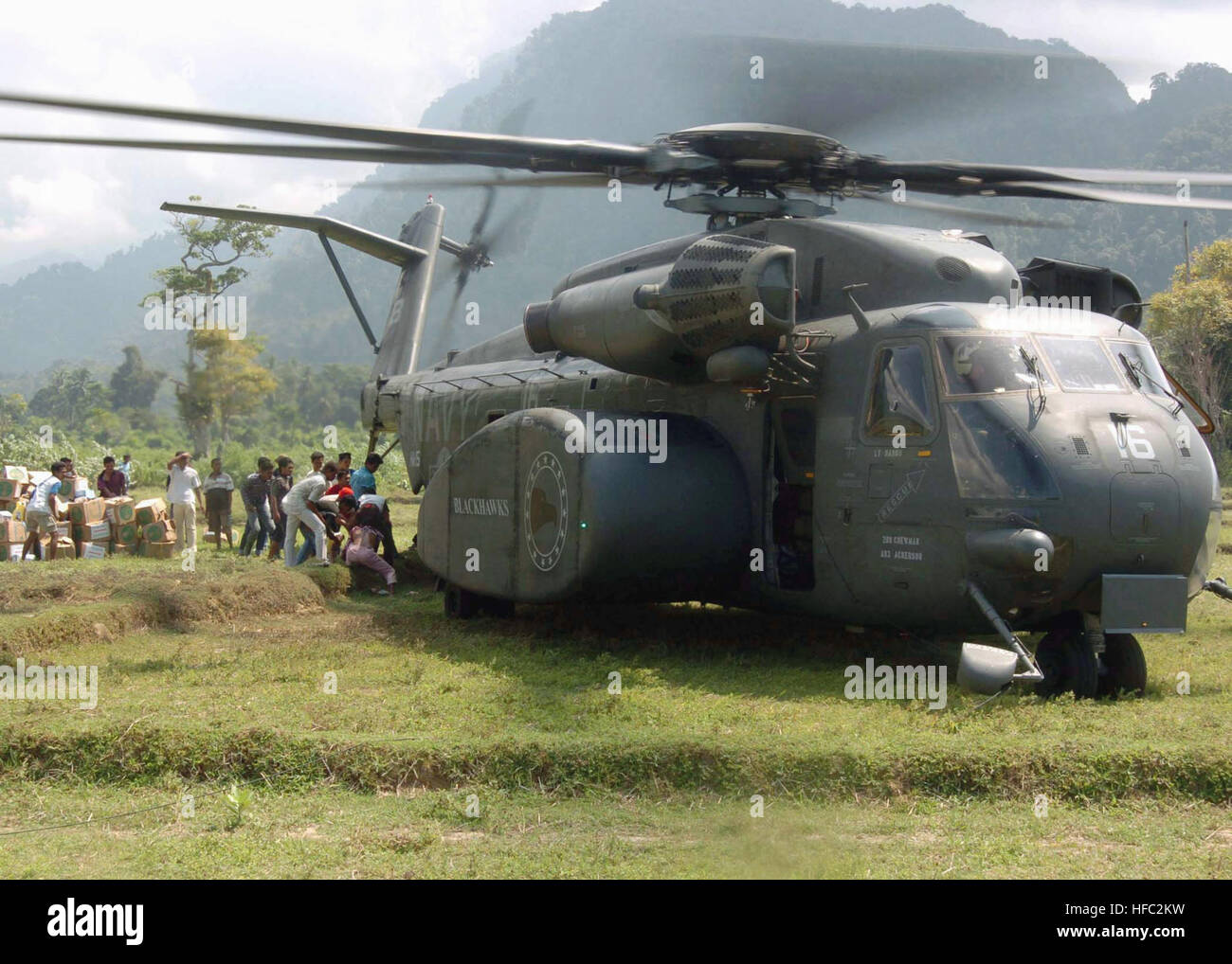 Les Indonésiens dans la ville de Sabang, Pulau Nous, Sumatra, Indonésie, décharger la nourriture, les vêtements, les fournitures de secours et de l'arrière d'un US Navy (USN) MH-53E Sea Dragon, Hélicoptère Helicopter Squadron 15 lutte contre les mines (HM-15), Blackhawks, Naval Station (NS) Norfolk, Virginie (VA). Le HM-15 est actuellement embarqué à bord de la classe Wasp navire d'assaut amphibie USS ESSEX (DG 2) [vivant], en cours à l'appui de l'opération UNIFIED ASSISTANCE, l'opération humanitaire d'efforts à la suite du tsunami qui a frappé l'Asie du Sud est le 26 décembre 2004. HM-15 offre des aides à la suite de la Sumatra 20 Banque D'Images