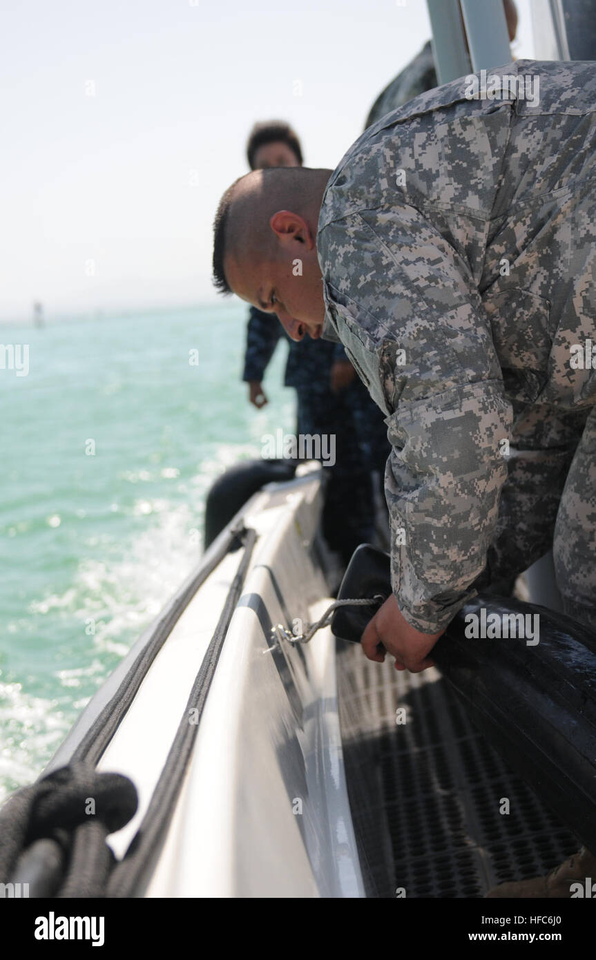 La CPS. Ronnie Escoto (avant), un soldat affecté à l'Équipe spéciale conjointe du Bureau des visiteurs de Guantanamo, attache un bouclier sur le côté d'un petit bateau de la marine pendant la traversée de la baie, le 11 juillet. Escoto travaille avec les marins de la base navale de la direction des opérations portuaires à l'appui de la Force opérationnelle des missions. Les opérations de sauvetage de petites embarcations 110711-N-MN220-074 Banque D'Images