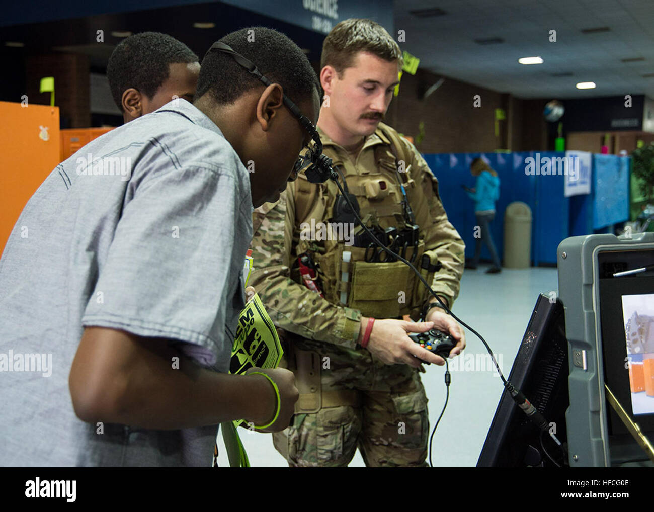Des explosifs et des munitions de 3e classe Dennis Blair, à gauche, à partir de la neutralisation des explosifs (unité mobile) EODMU 6, montre comment un étudiant à l'utilisation de la télécommande et l'appareil photo casque pour un système robotique transportable PackBot au Portsmouth Public Schools Science, technologie, ingénierie et mathématiques (STIM) journée événement tenu au Woodrow Wilson High School. Des marins du EODMU 6 et mobile et l'Unité de plongée de récupération (MDSU) 2 a appuyé l'approche communautaire en fournissant une occasion pour les élèves et leurs familles à voir et interagir avec EOD et Marine matériel de plongée de la Marine et des robots à l'événement Banque D'Images