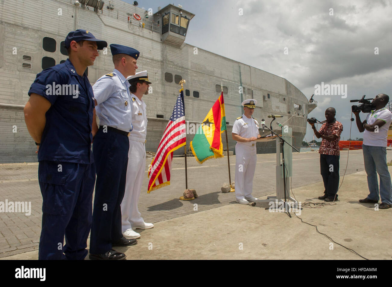 140411-N-ZY039-099 SEKONDI, Ghana (11 avril 2014) U.S. Coast Guard Le Lieutenant Jeffrey Deitel, gauche, détachement de l'application de la loi responsable de la Garde côtière des États-Unis, le lieutenant Cmdr. John Carter, l'application du droit maritime de l'Afrique Société de l'agent responsable de l'établissement, et le Capitaine Doug Casavant, civil service maître du transport maritime militaire conjointe commande bateau à grande vitesse l'USNS Lance (JHSV 1), regard sur la marine américaine comme le Capt Marc Lederer, commandant de la mission de Spearhead, donne un discours lors de la cérémonie de clôture pour le partenariat pour l'application du droit maritime. Le partenariat est la phase opérationnelle du Partenariat Afrique Banque D'Images