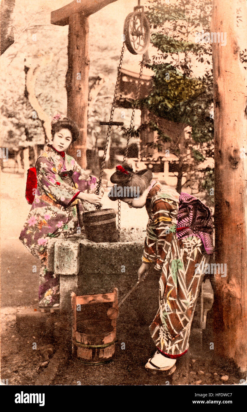 19e siècle carte postale japonaise couleur sépia part. Deux femmes en kimono élever l'eau d'un bien à l'extérieur. Banque D'Images